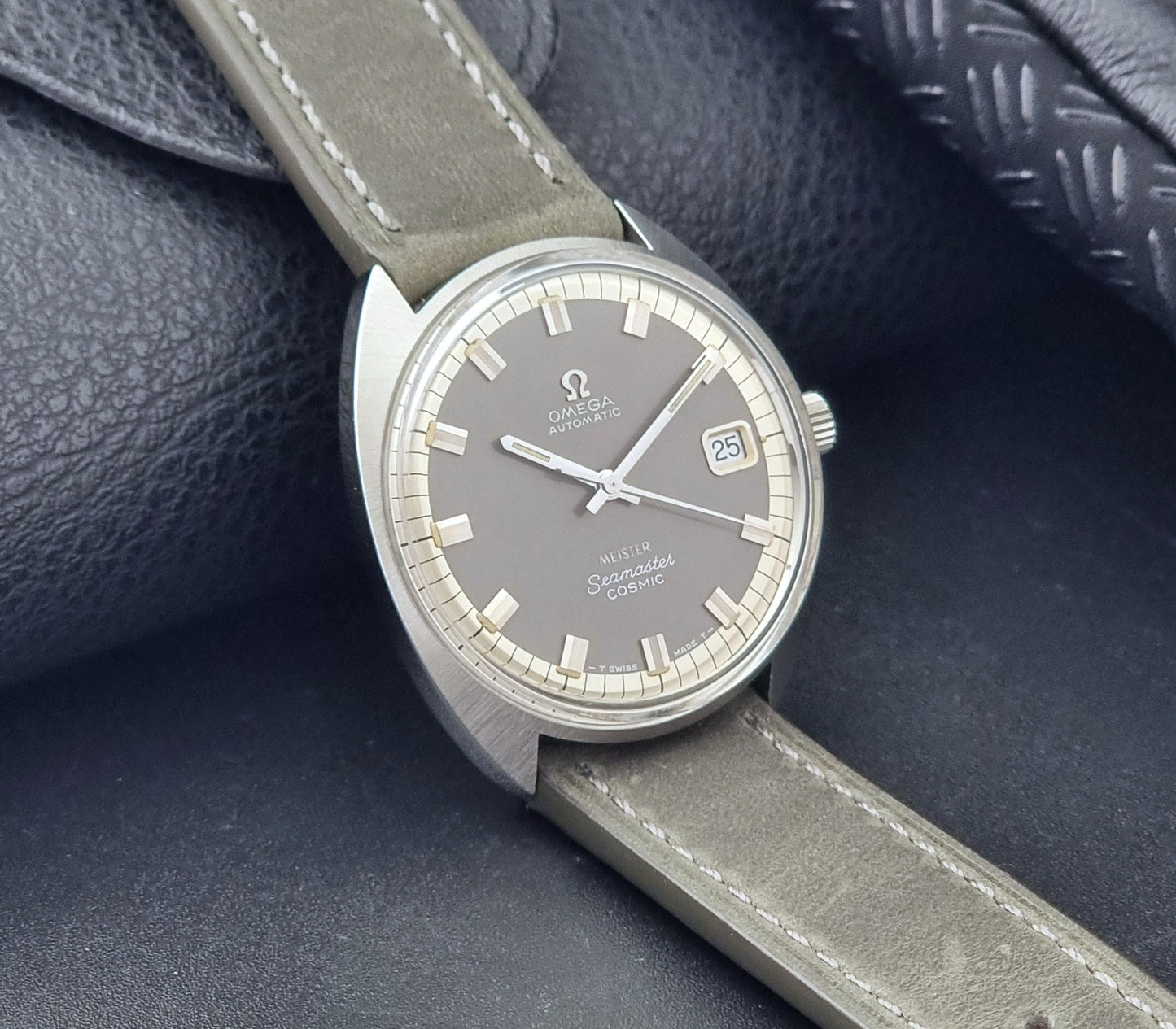 Vintage Omega Seamaster Cosmic 166.026 Wristwatch Meister Dial with leather strap on a dark gray background side view