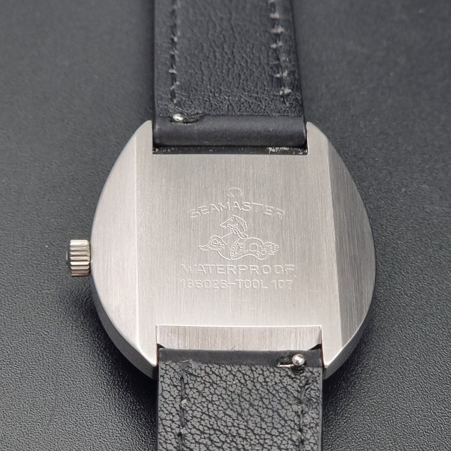 Vintage Omega Wristwatch Seamaster Cosmic 166.026 with silver dial and black leather strap on a gray background case back