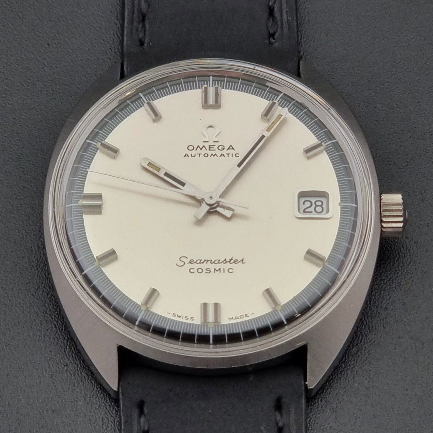 Vintage Omega Wristwatch Seamaster Cosmic 166.026 with silver dial and black leather strap on a gray background close up