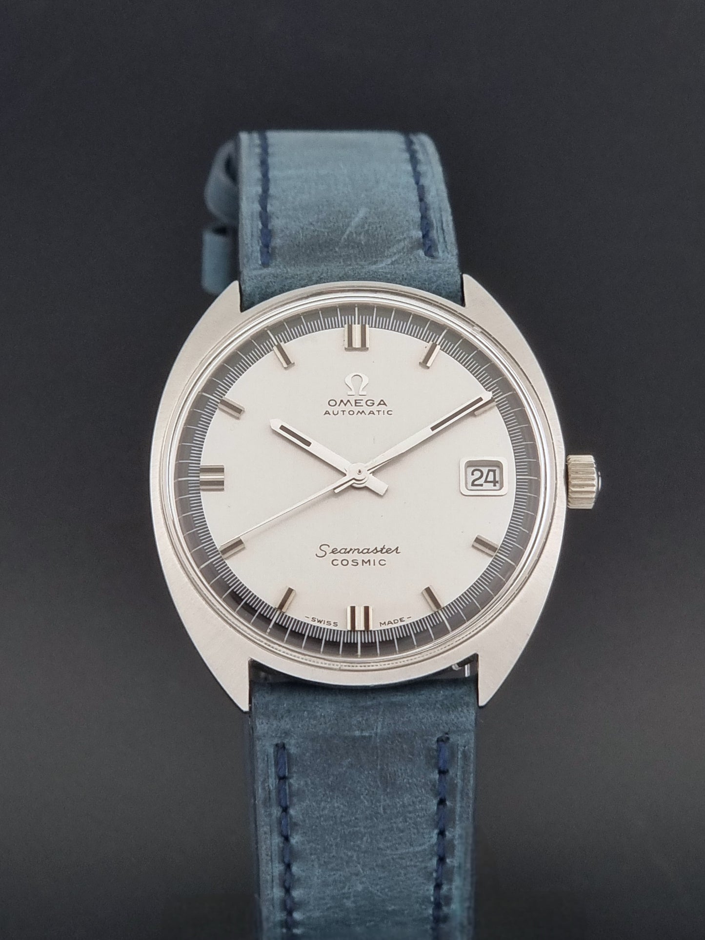 Vintage Omega 166.026 Seamaster Cosmic Wristwatch with blue leather strap and silver case on a dark gray background close dial view