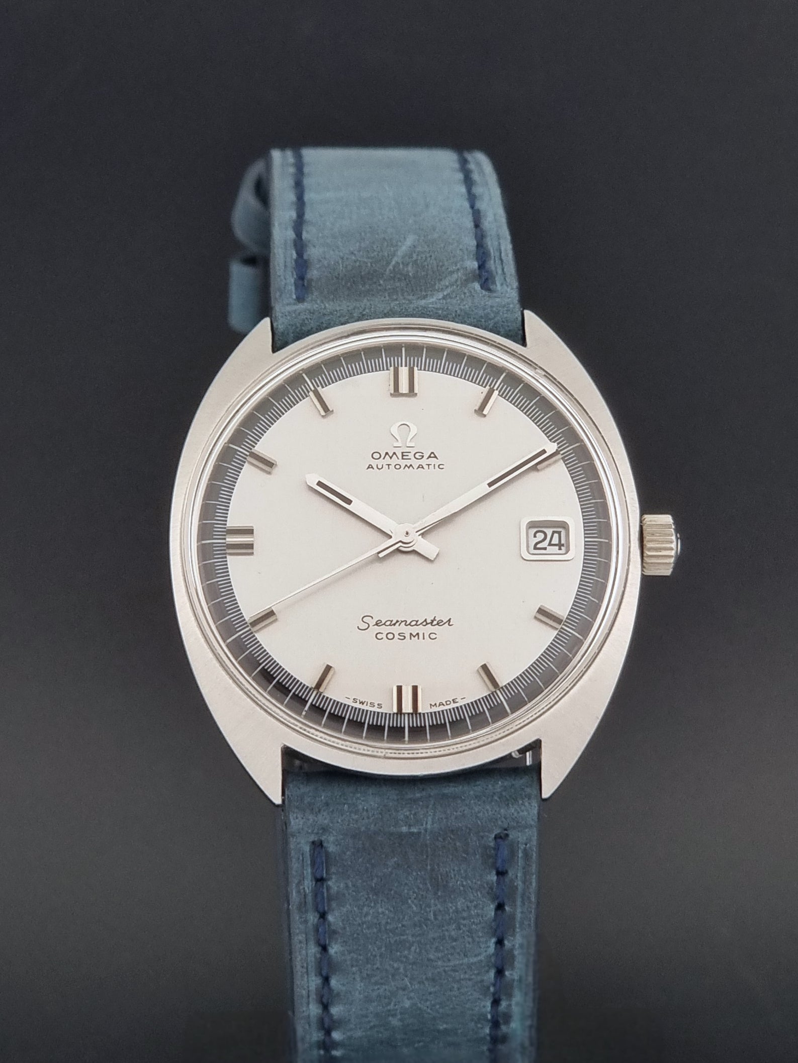 Vintage Omega 166.026 Seamaster Cosmic Wristwatch with blue leather strap and silver case on a dark gray background close dial view