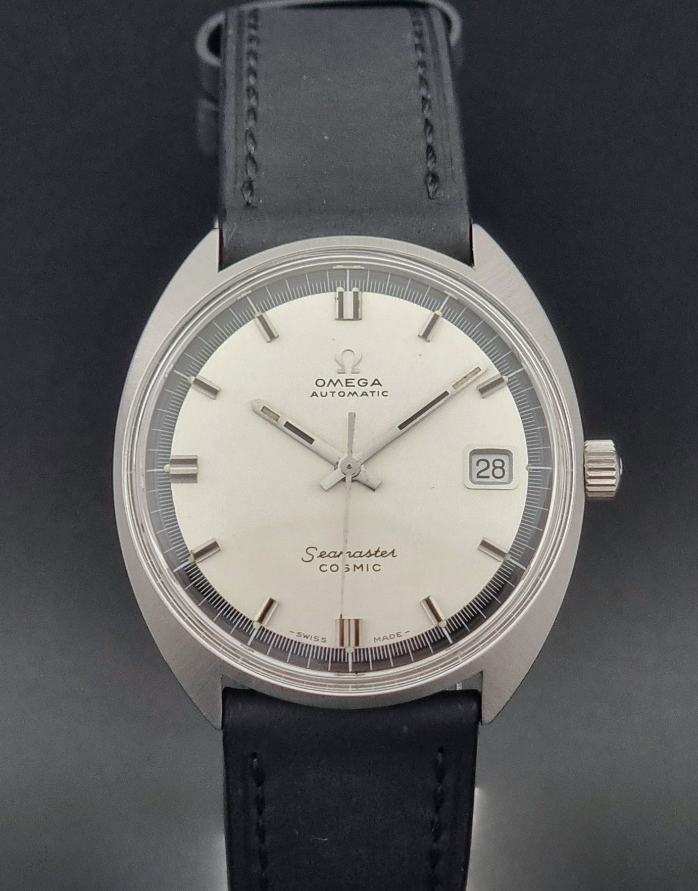 Vintage Omega Wristwatch Seamaster Cosmic 166.026 with silver dial and black leather strap on a gray background dial close up