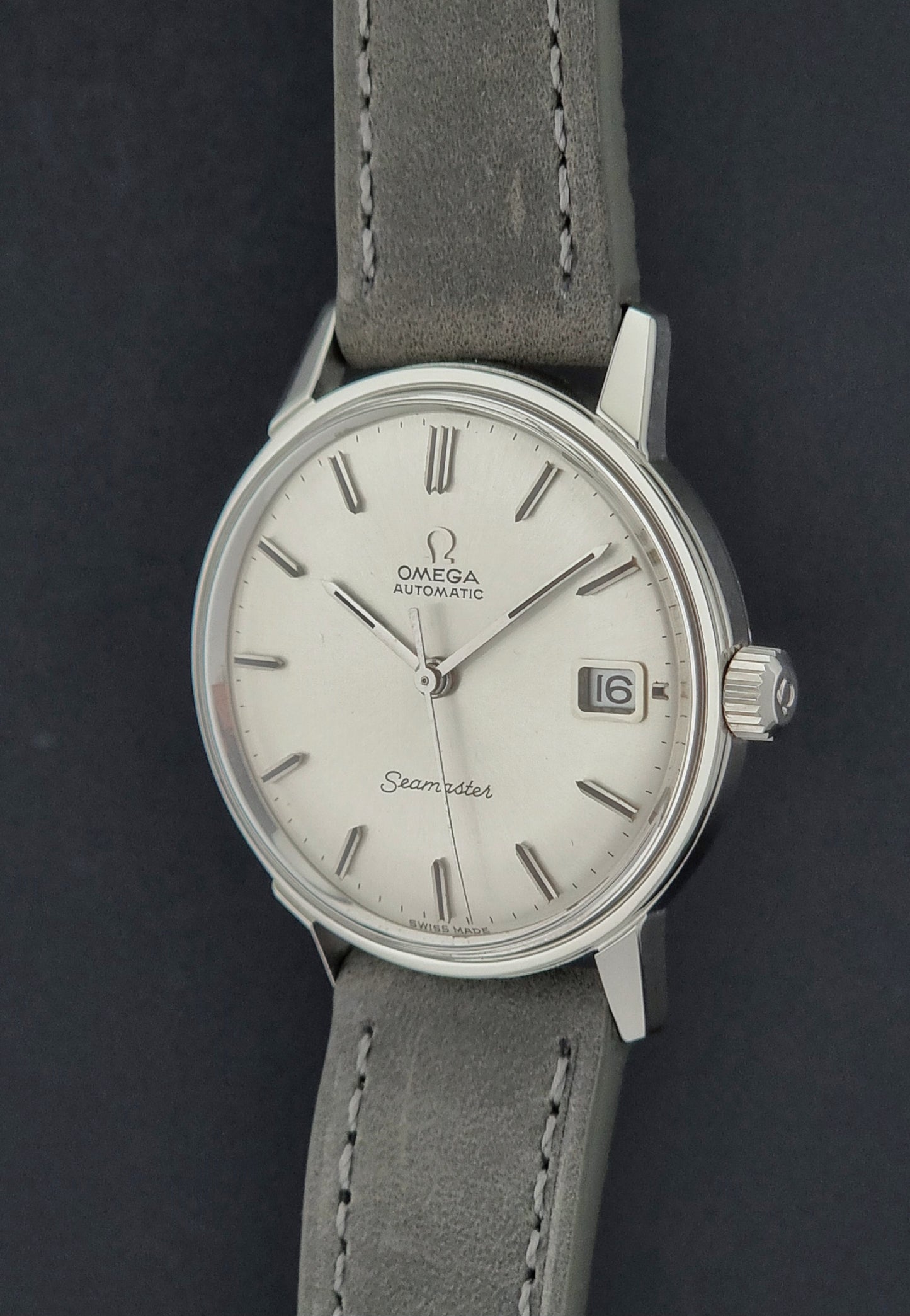 Vintage Omega Seamaster Wristwatch 166.037 with a dark leather strap on a gray background crown profile view