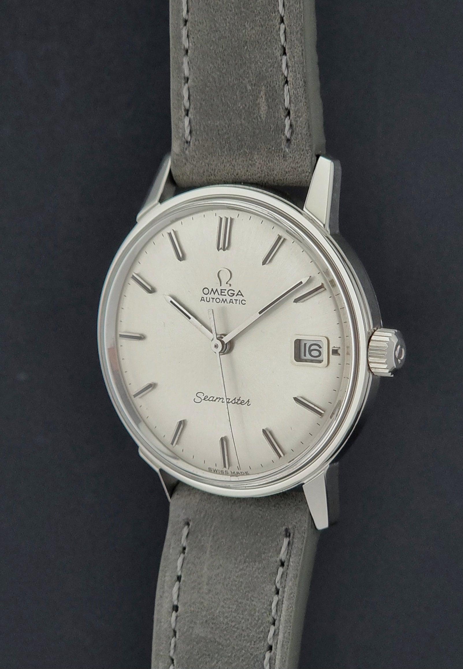 Vintage Omega Seamaster Wristwatch 166.037 with a dark leather strap on a gray background crown profile view