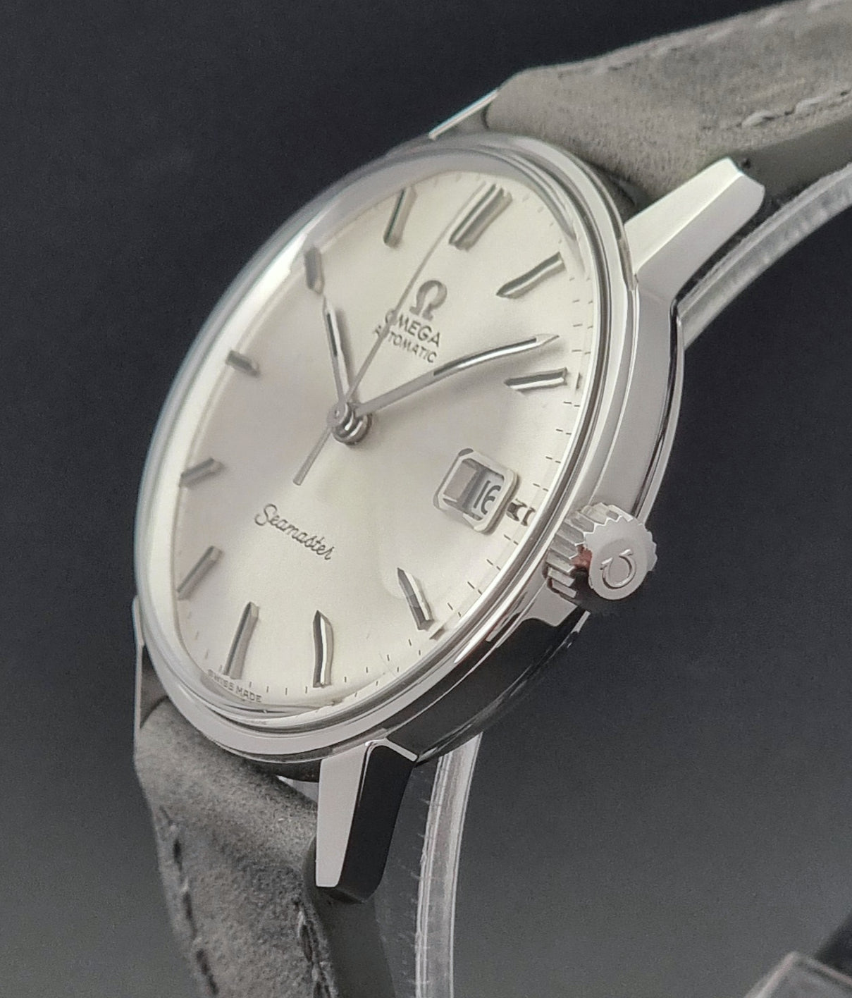 Vintage Omega Seamaster Wristwatch 166.037 with a dark leather strap on a gray background crown side profile