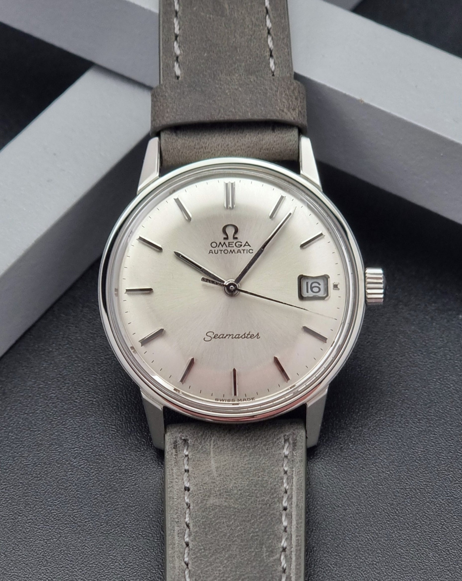 Vintage Omega Seamaster Wristwatch 166.037 with a dark leather strap on a gray background front