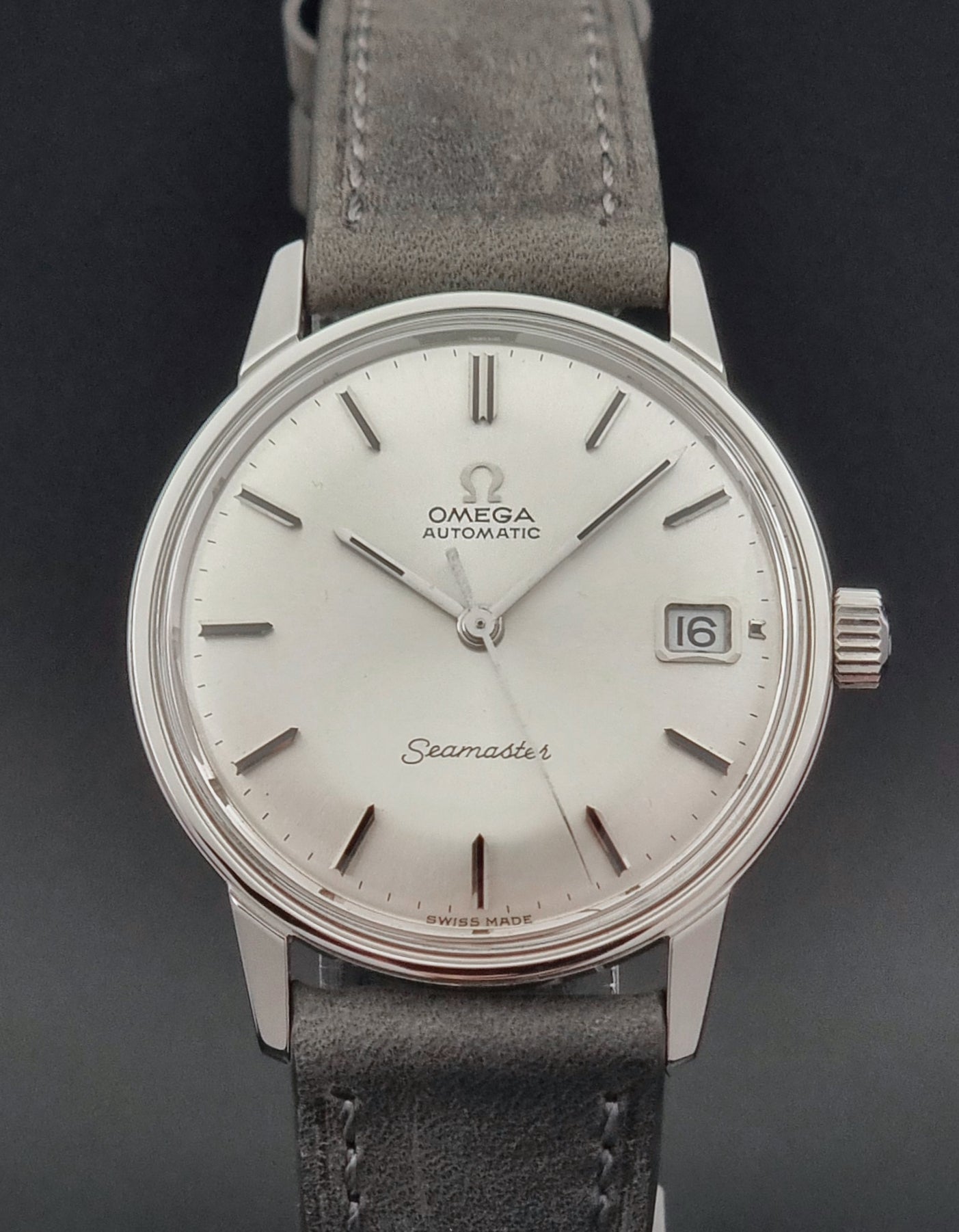 Vintage Omega Seamaster Wristwatch 166.037 with a dark leather strap on a gray background dial close up