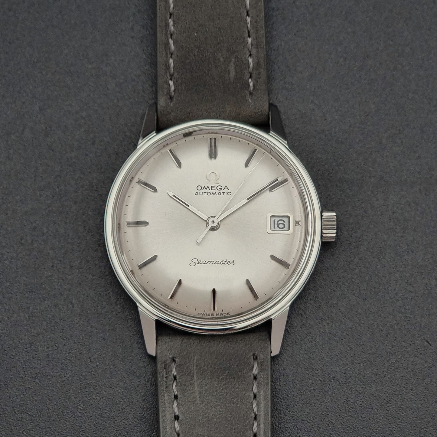 Vintage Omega Seamaster Wristwatch 166.037 with a dark leather strap on a gray background front view