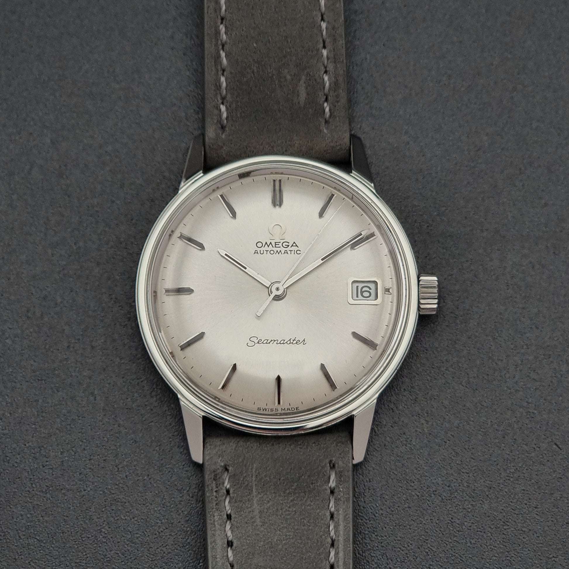 Vintage Omega Seamaster Wristwatch 166.037 with a dark leather strap on a gray background front view