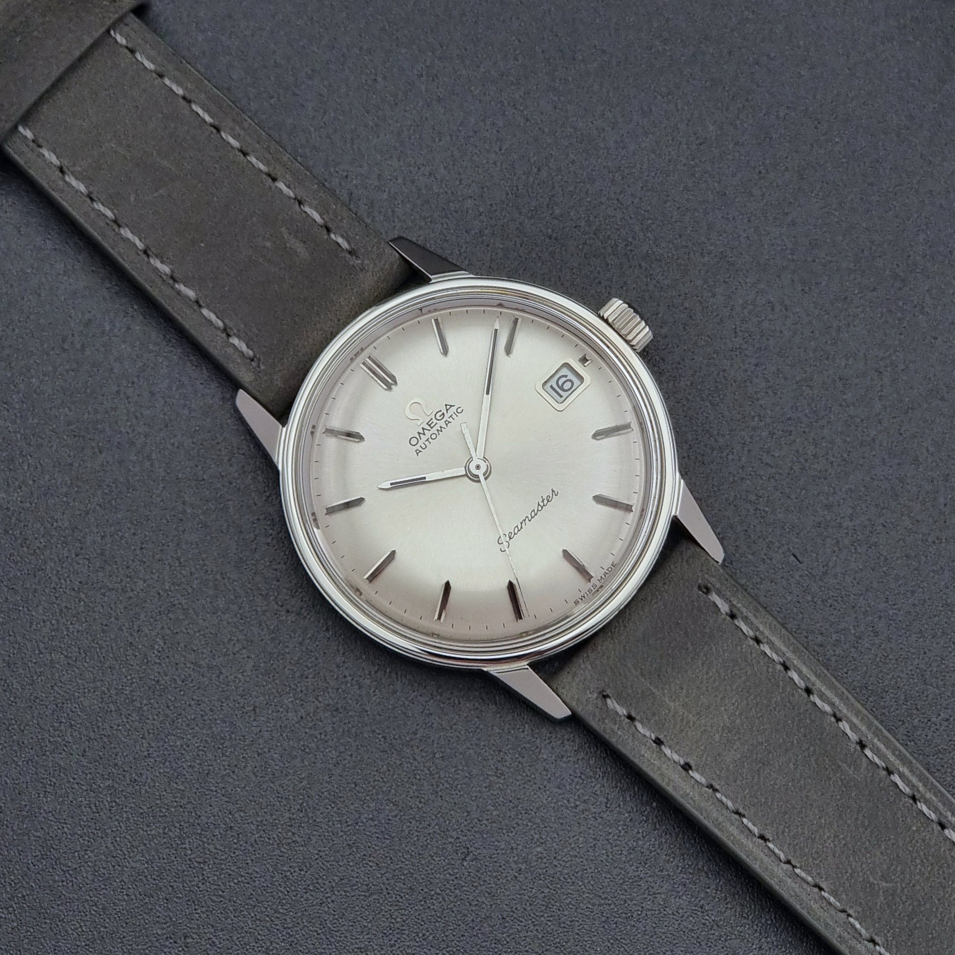 Vintage Omega Seamaster Wristwatch 166.037 with a dark leather strap on a gray background