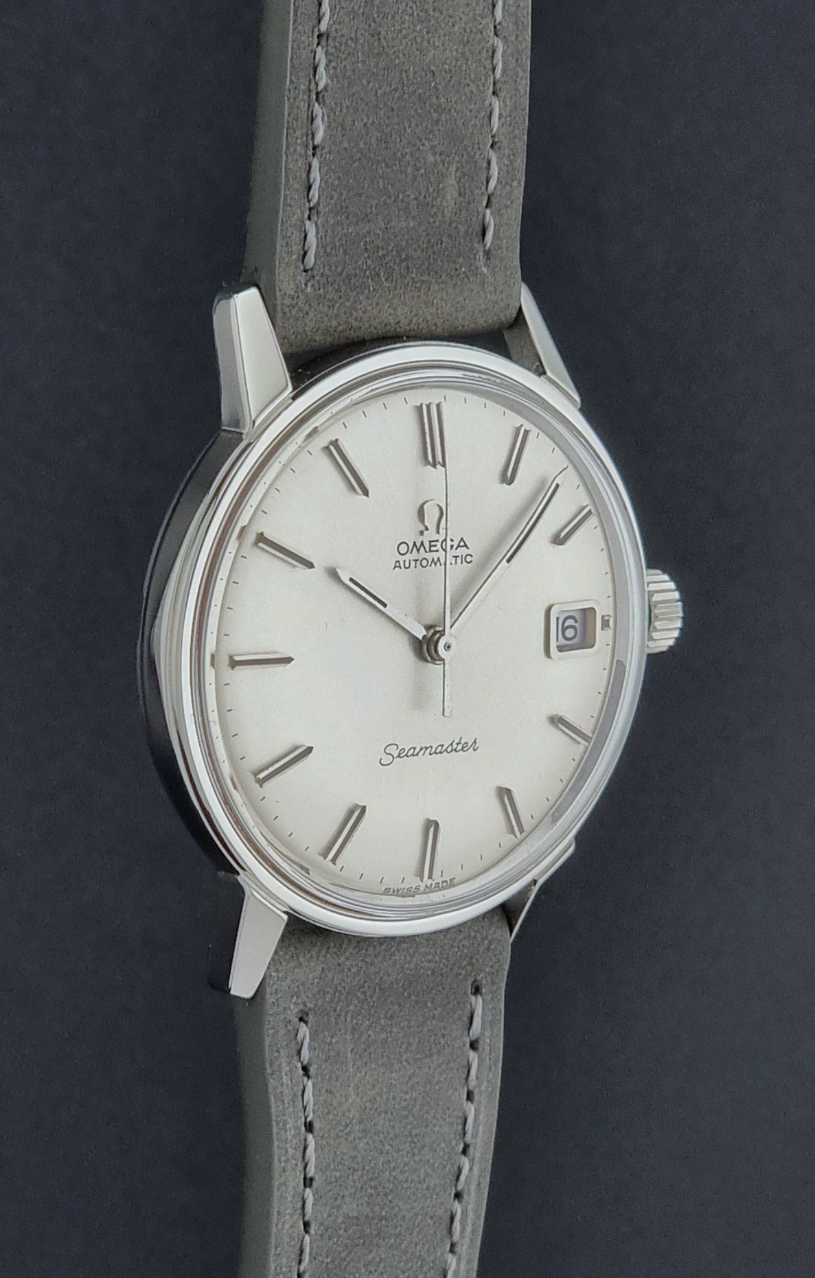 Vintage Omega Seamaster Wristwatch 166.037 with a dark leather strap on a gray background profile view