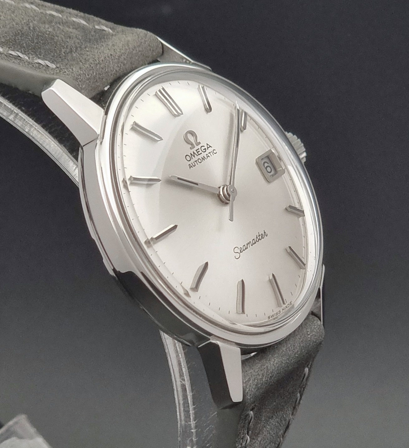 Vintage Omega Seamaster Wristwatch 166.037 with a dark leather strap on a gray background side profile