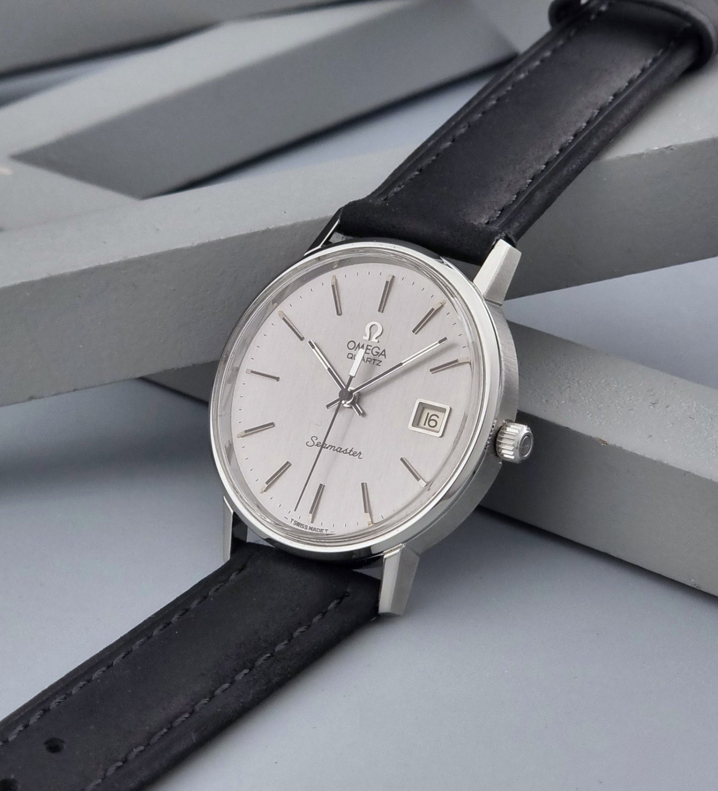 Vintage Omega Quartz Wristwatch Seamaster 196.0079 watch with a black strap on a gray background crown view