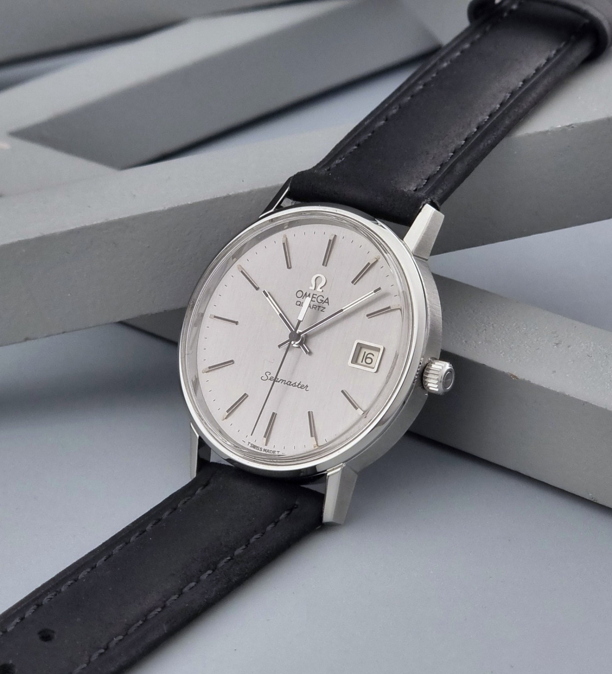 Vintage Omega Quartz Wristwatch Seamaster 196.0079 watch with a black strap on a gray background crown view