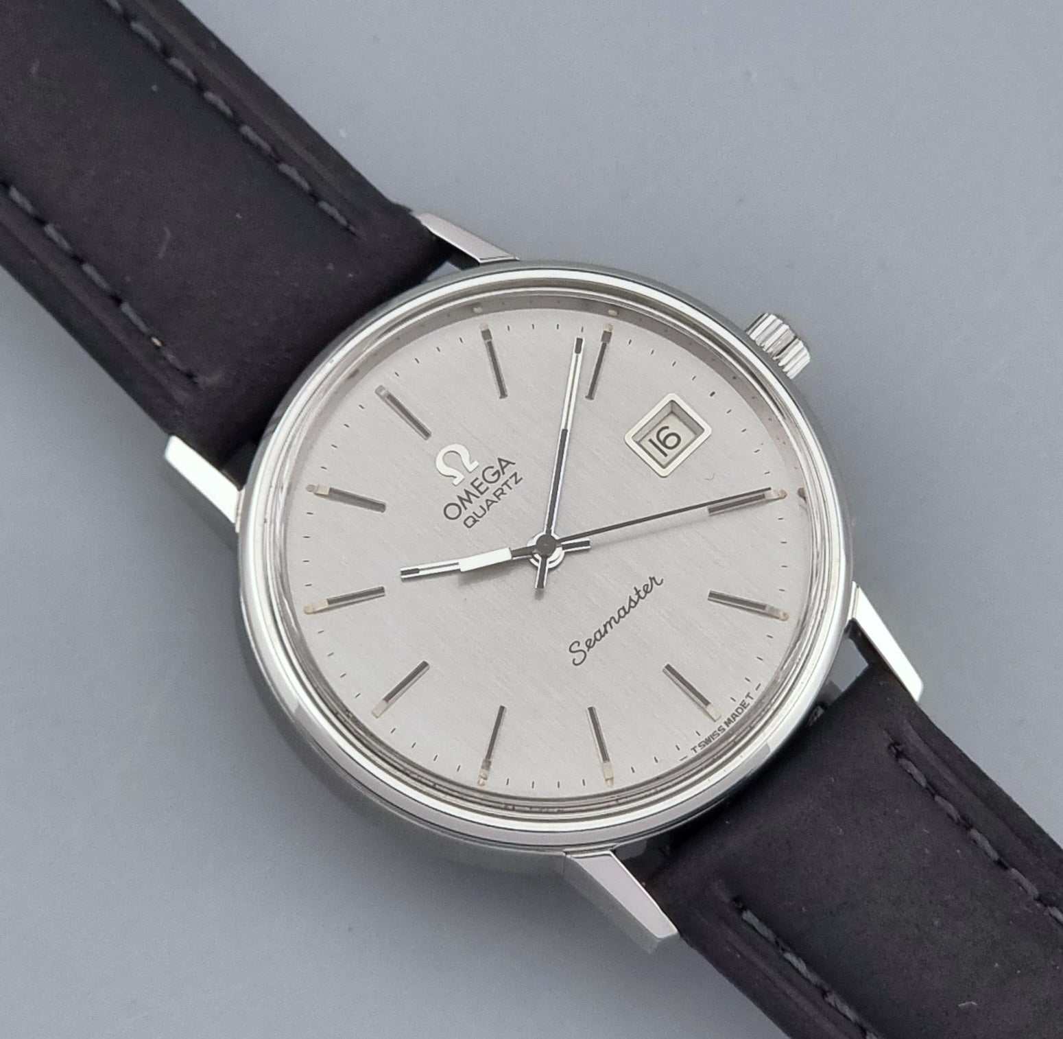 Vintage Omega Quartz Wristwatch Seamaster 196.0079 watch with a black strap on a gray background front view