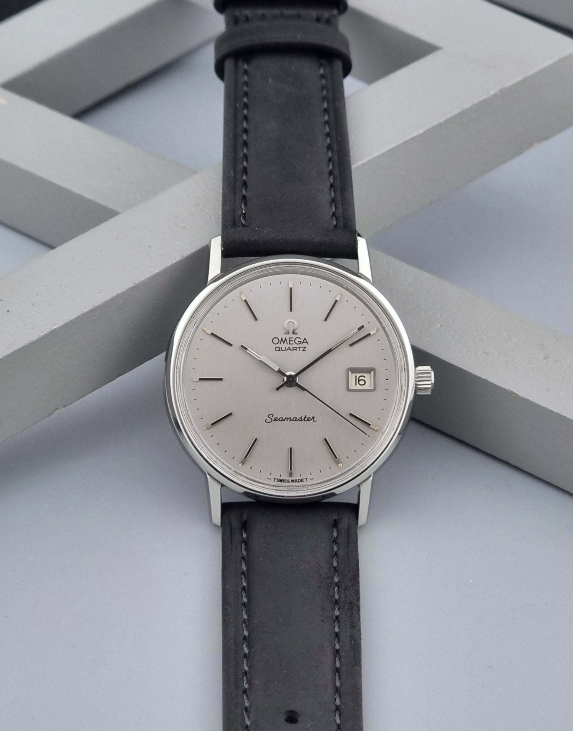 Vintage Omega Quartz Wristwatch Seamaster 196.0079 watch with a black strap on a gray background dial view