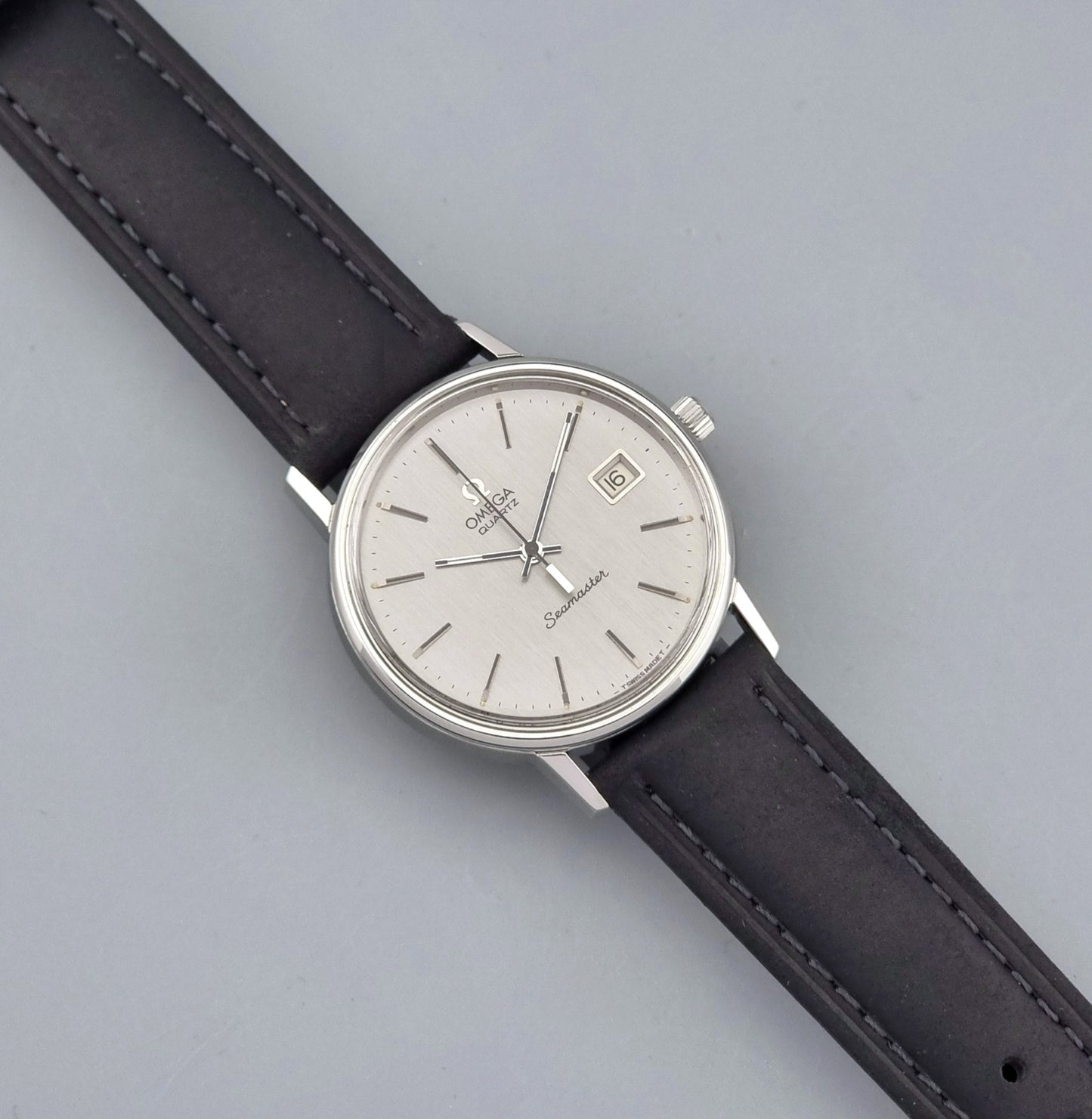 Vintage Omega Quartz Wristwatch Seamaster 196.0079 watch with a black strap on a gray background dial