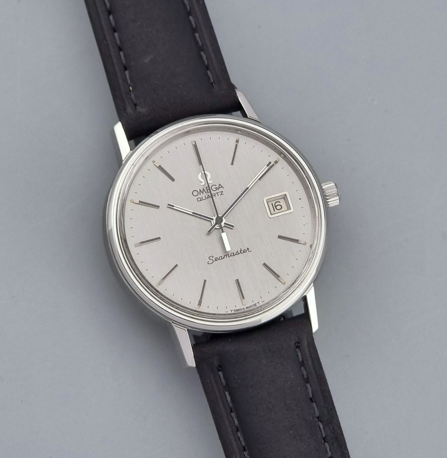 Vintage Omega Quartz Wristwatch Seamaster 196.0079 watch with a black strap on a gray background close up dial view