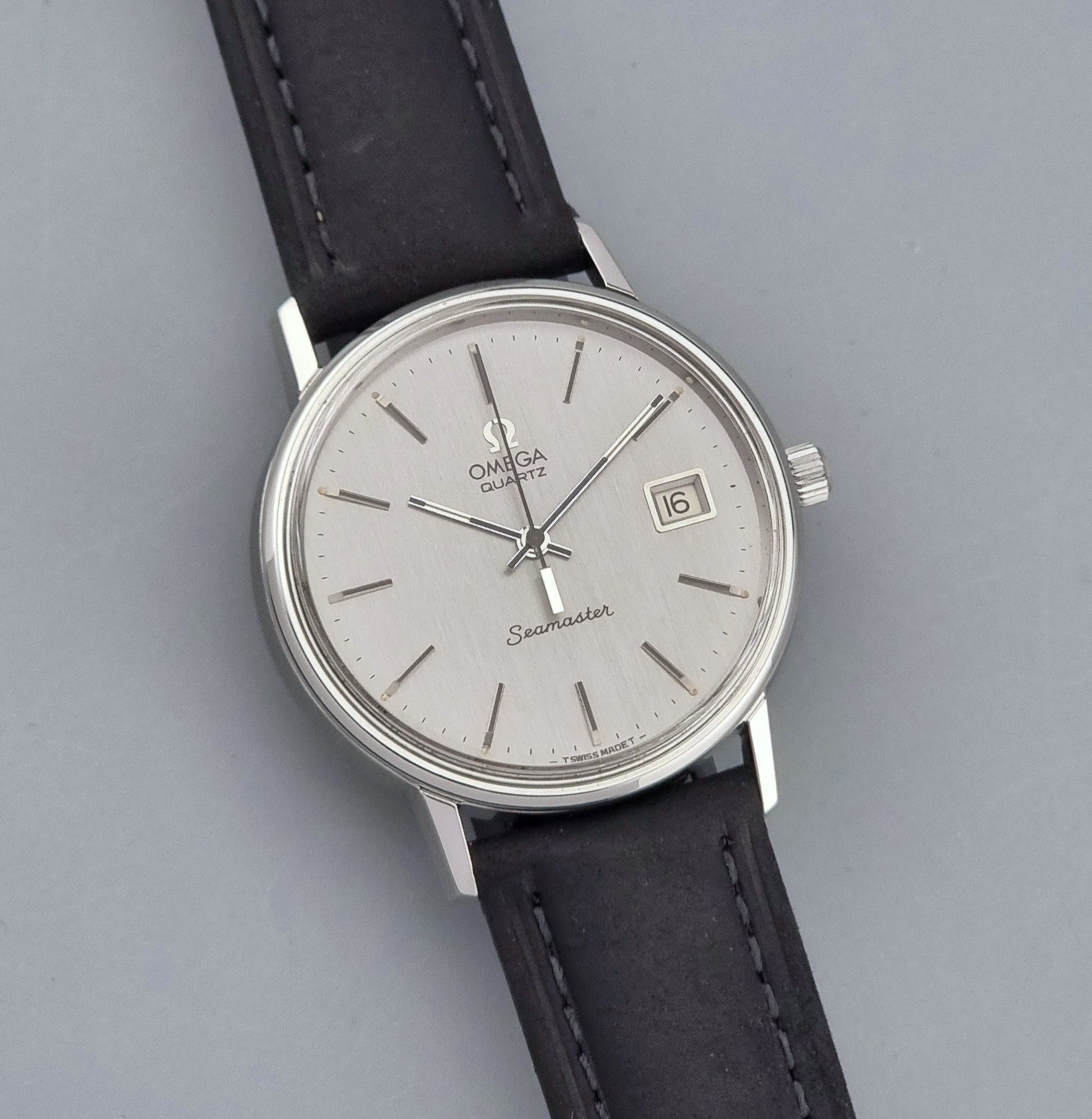Vintage Omega Quartz Wristwatch Seamaster 196.0079 watch with a black strap on a gray background close up dial view