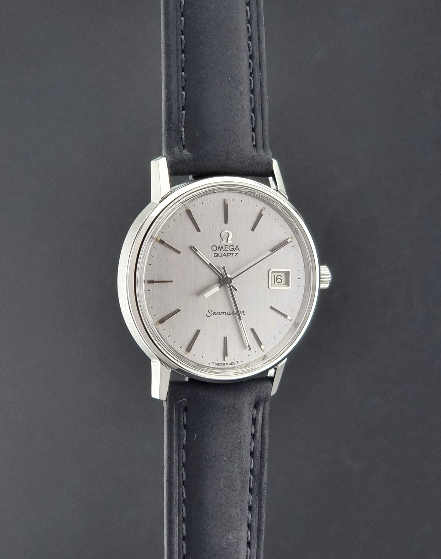 Vintage Omega Quartz Wristwatch Seamaster 196.0079 watch with a black strap on a gray background side profile view