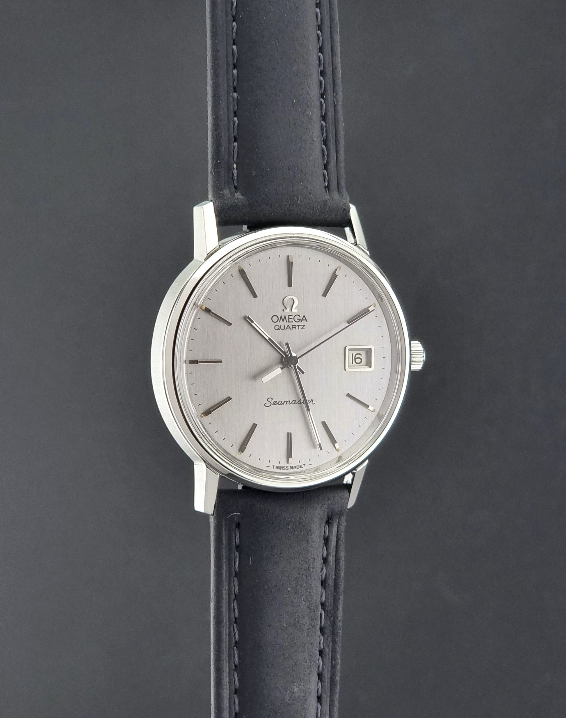 Vintage Omega Quartz Wristwatch Seamaster 196.0079 watch with a black strap on a gray background side profile view