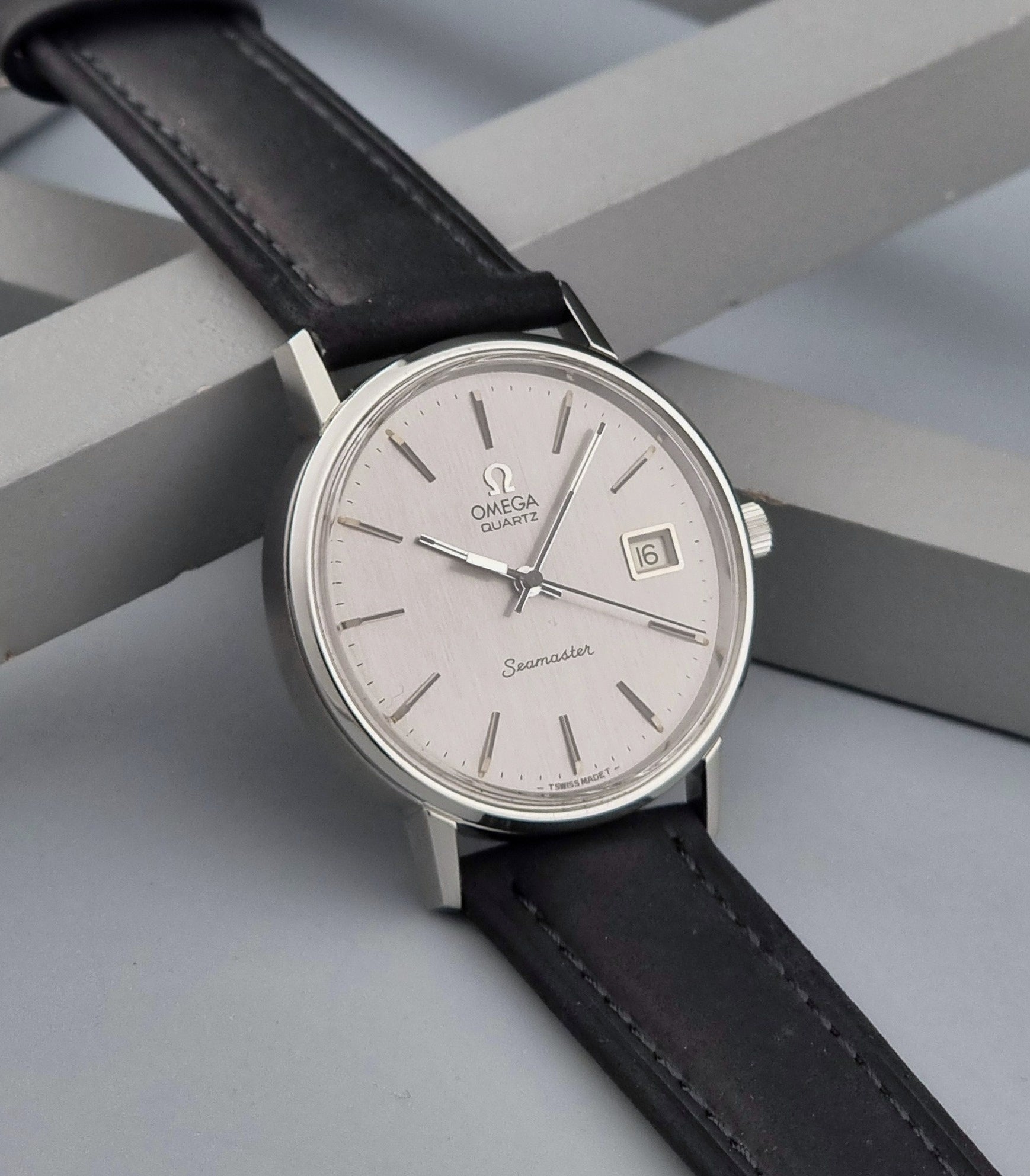Vintage Omega Quartz Wristwatch Seamaster 196.0079 watch with a black strap on a gray background side view