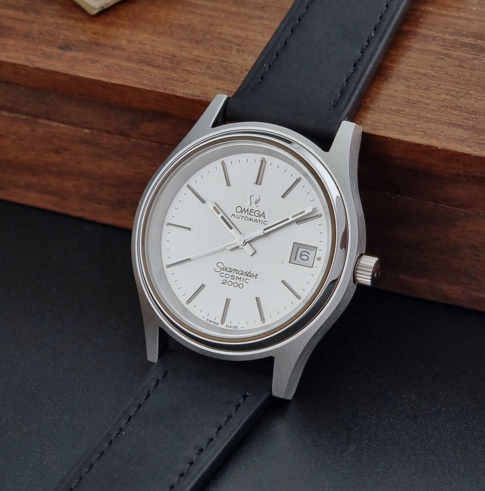 Vintage Omega Wristwatch Seamaster Cosmic 2000 Jumbo 166.128 watch with black leather strap on a wooden surface crown view