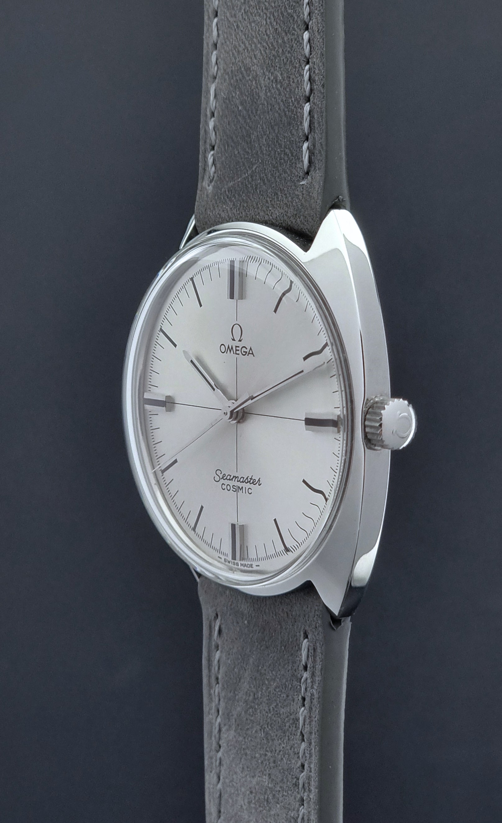 Omega watch with silver case and gray leather strap on a dark background crown side profile