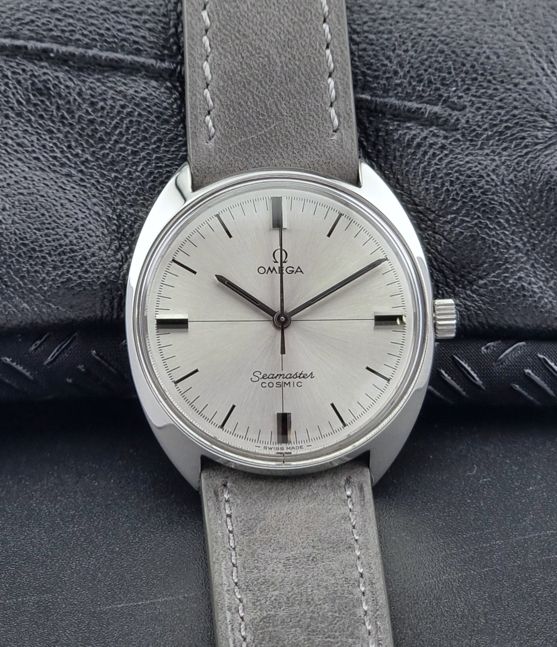 Omega Seamaster Cosmic watch with gray leather strap on textured surface