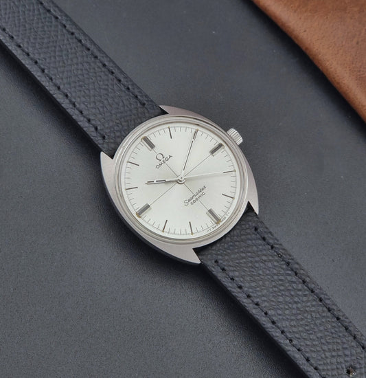 Vintage Omega Seamaster Cosmic 135.017 watch with a white face on a dark surface dial