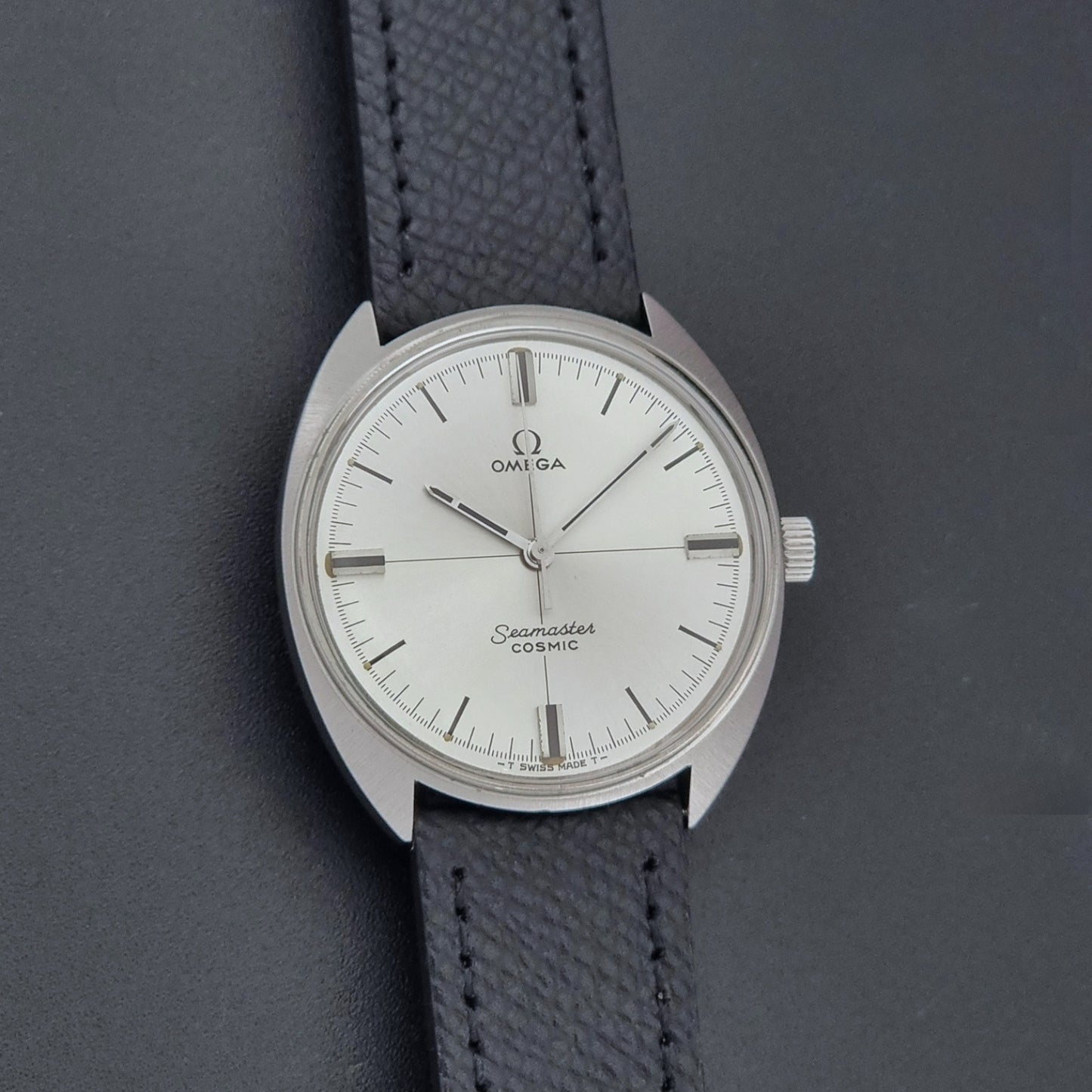 Vintage Omega Seamaster Cosmic 135.017 watch with a white face on a dark surface front view