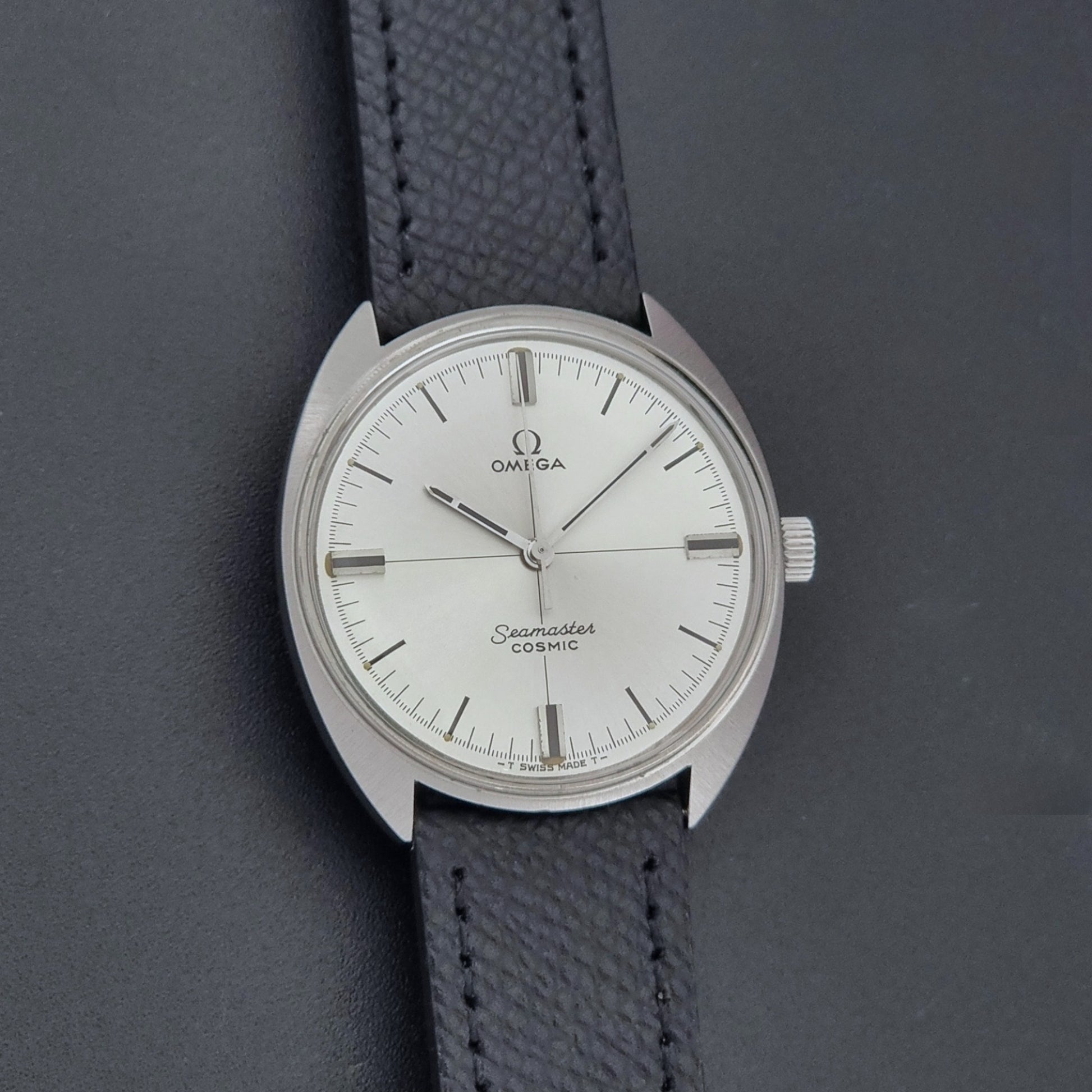 Vintage Omega Seamaster Cosmic 135.017 watch with a white face on a dark surface front view