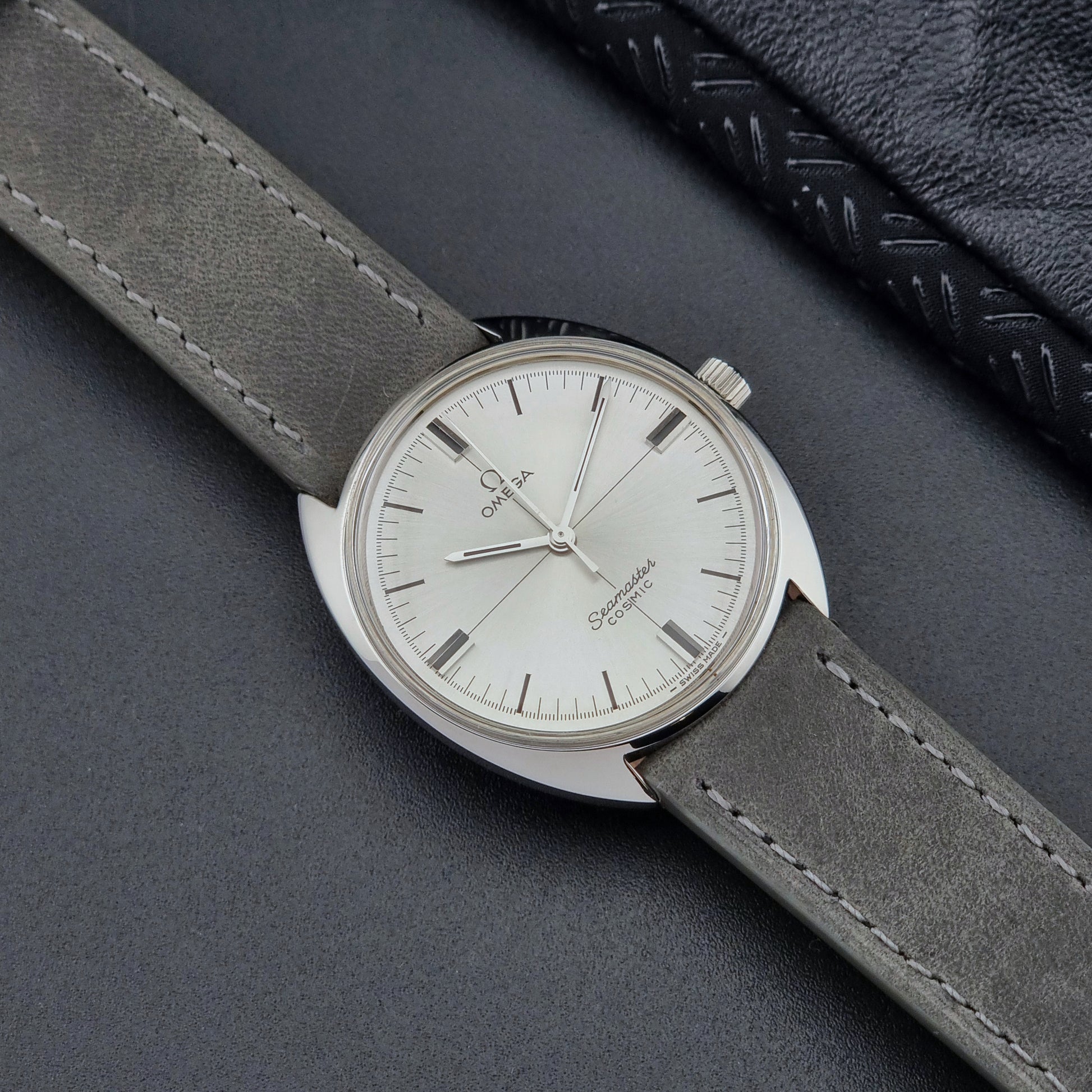 Omega Watch Seamaster Cosmic Crosshair Dial with gray strap on a dark surface