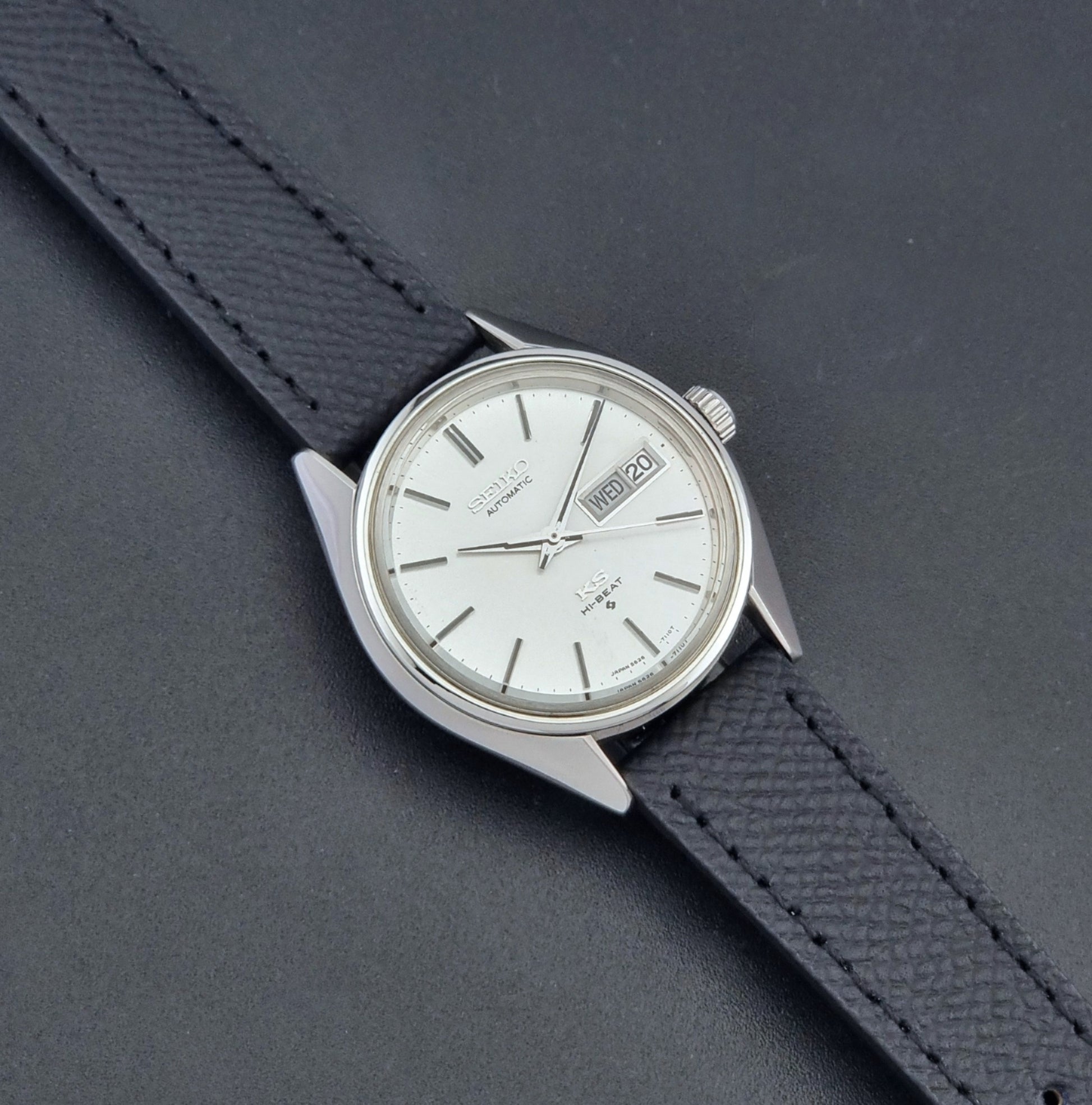Vintage King Seiko 5626-7110 Wristwatch with a silver case and black strap on a dark gray background dial