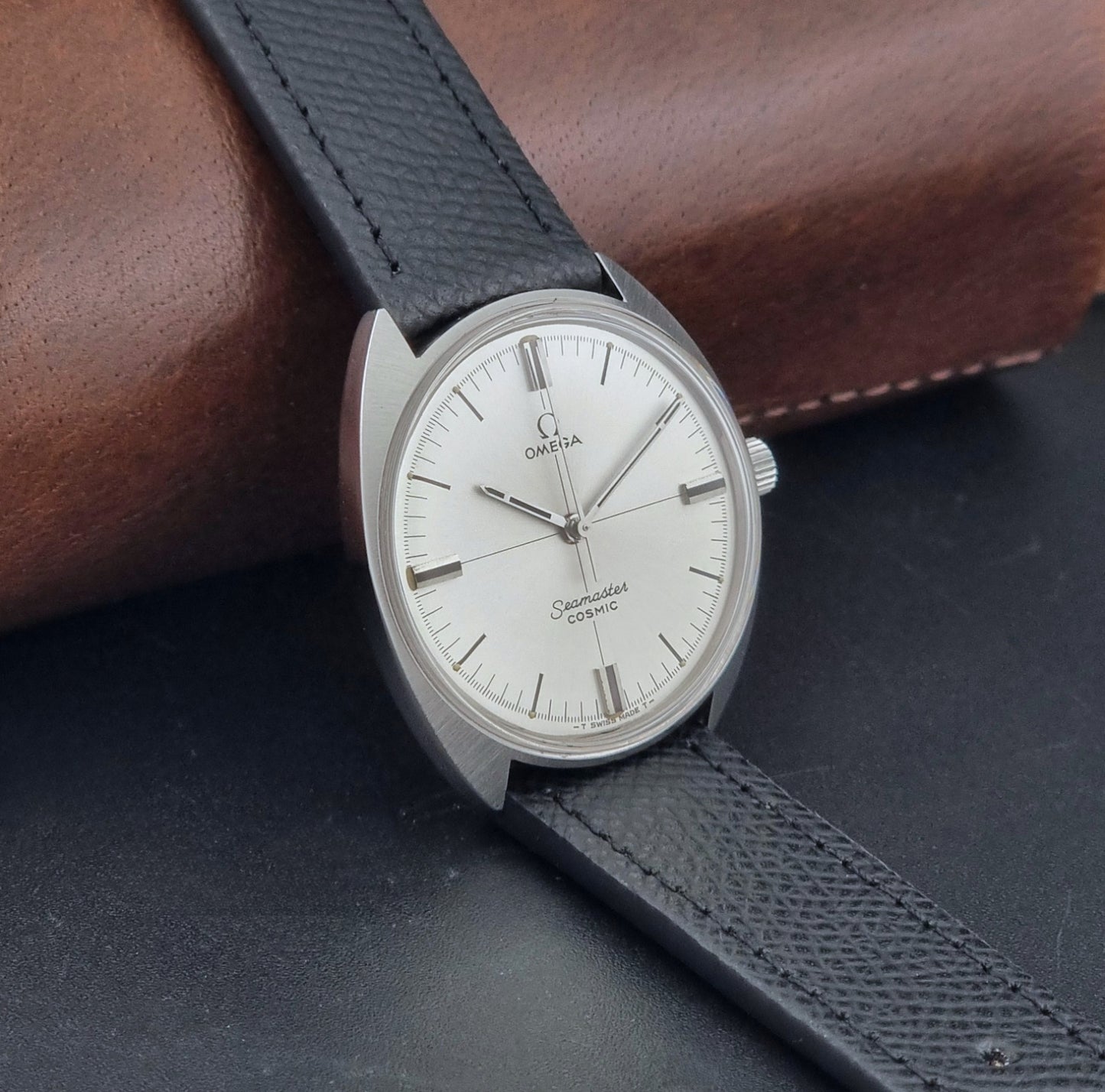 Vintage Omega Seamaster Cosmic 135.017 watch with a white face on a dark surface side view