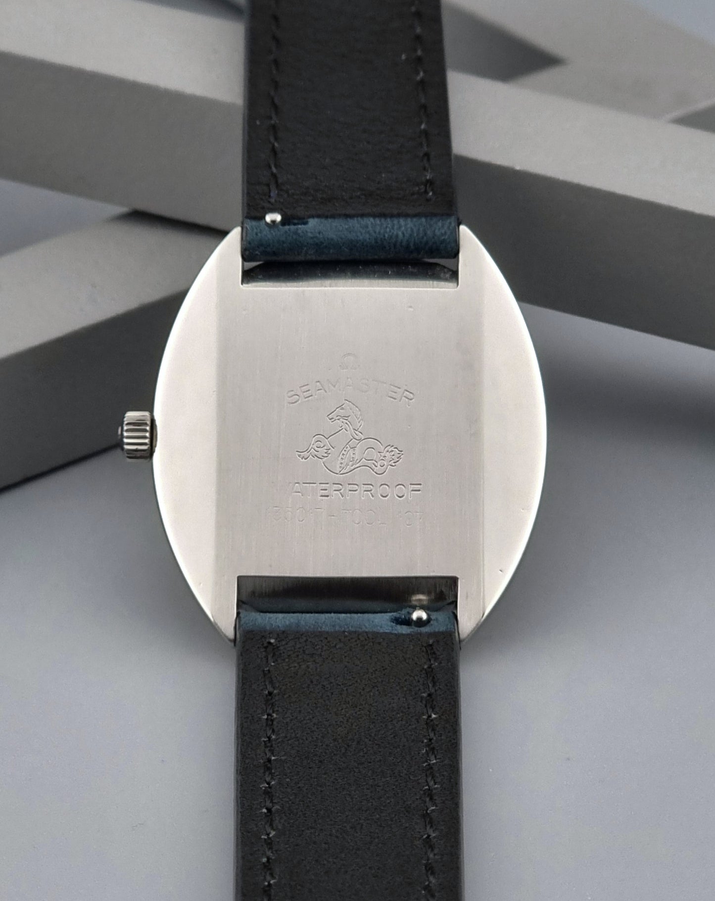 Vintage Omega Wristwatch Seamaster Cosmic 135.017 with blue leather strap on a gray background case back view