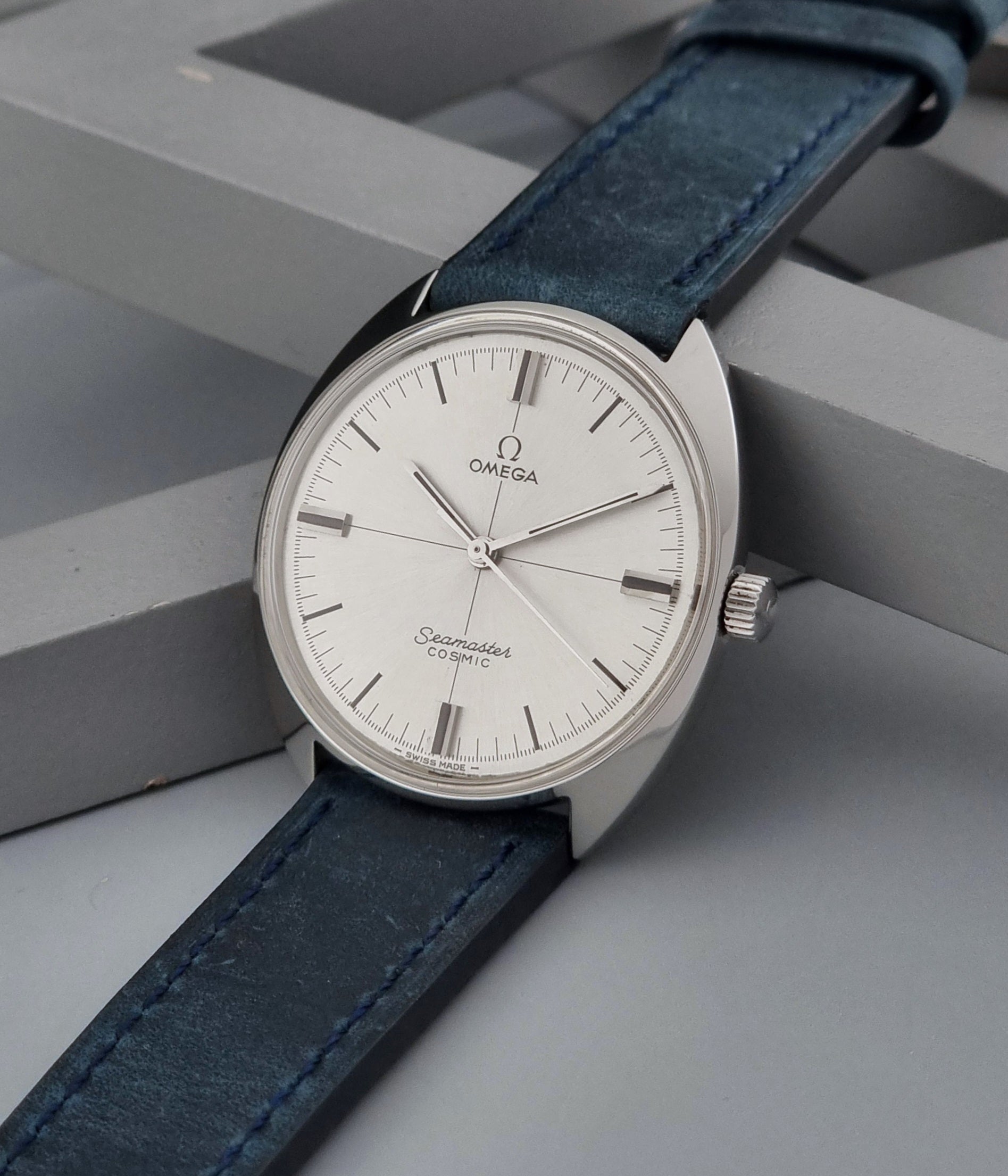 Vintage Omega Wristwatch Seamaster Cosmic 135.017 with blue leather strap on a gray background crown view