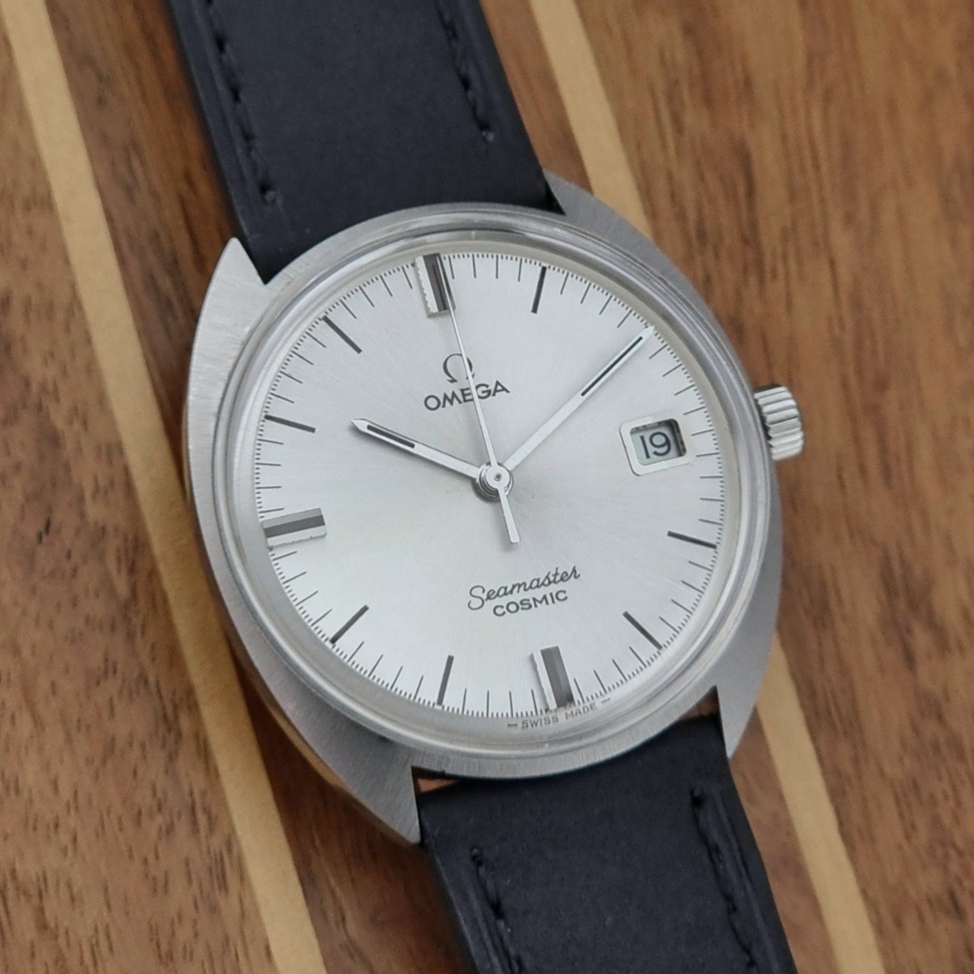 Omega Seamaster Cosmic 136.017 watch with black leather strap on a wooden surface