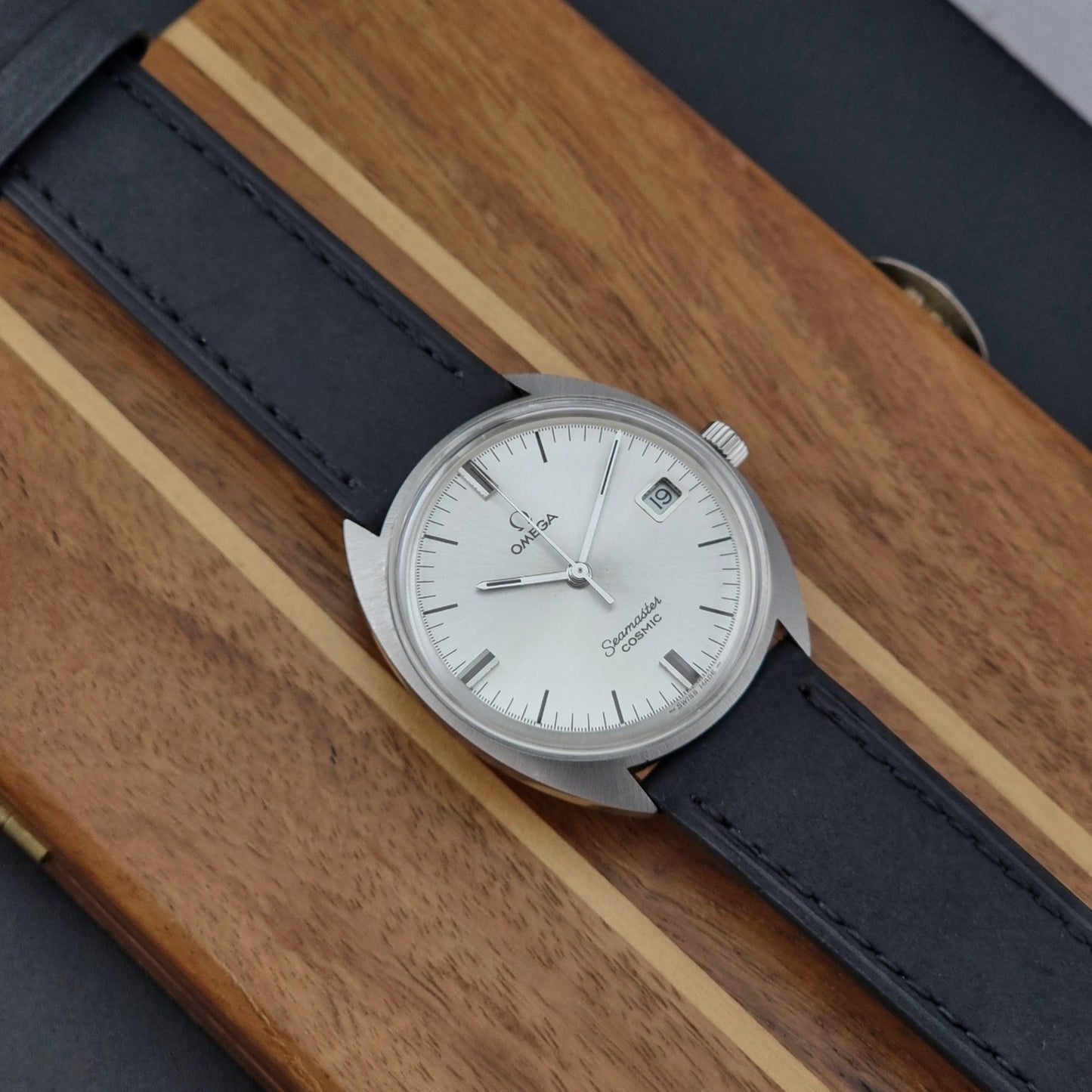 Omega Seamaster Cosmic 136.017 watch with black leather strap on a wooden surface