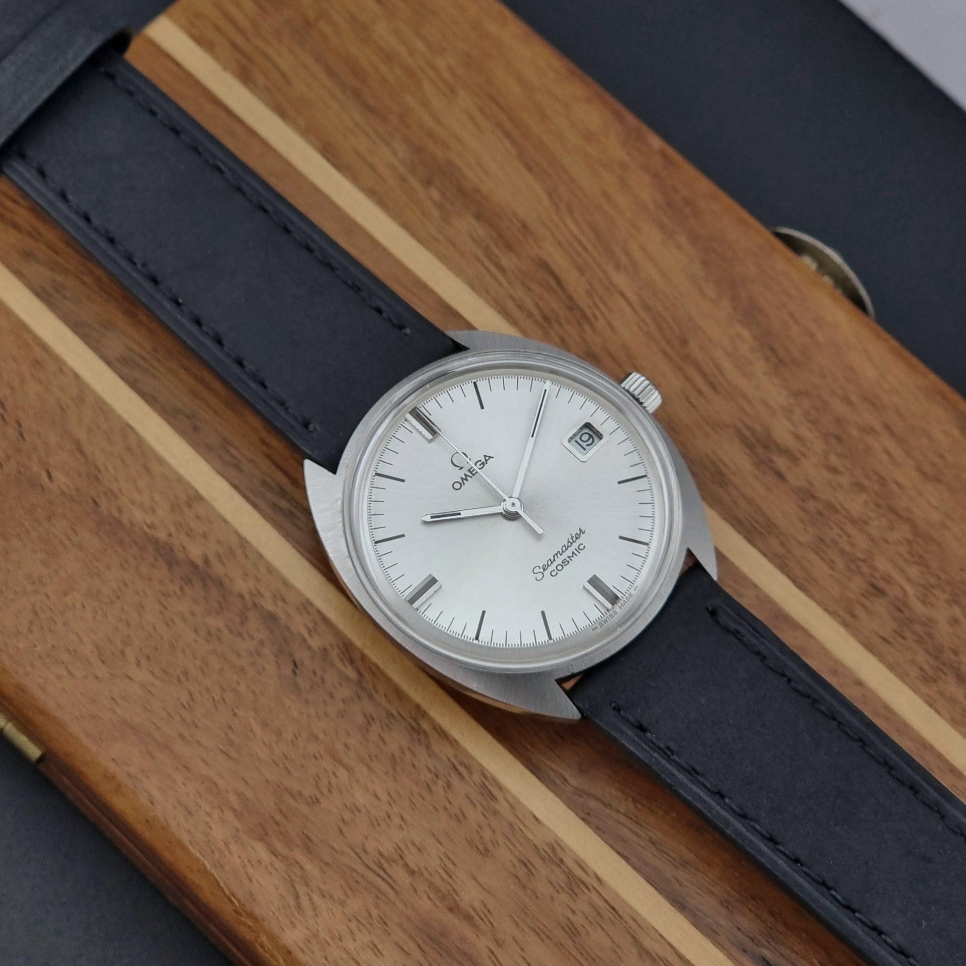 Omega Seamaster Cosmic 136.017 watch with black leather strap on a wooden surface