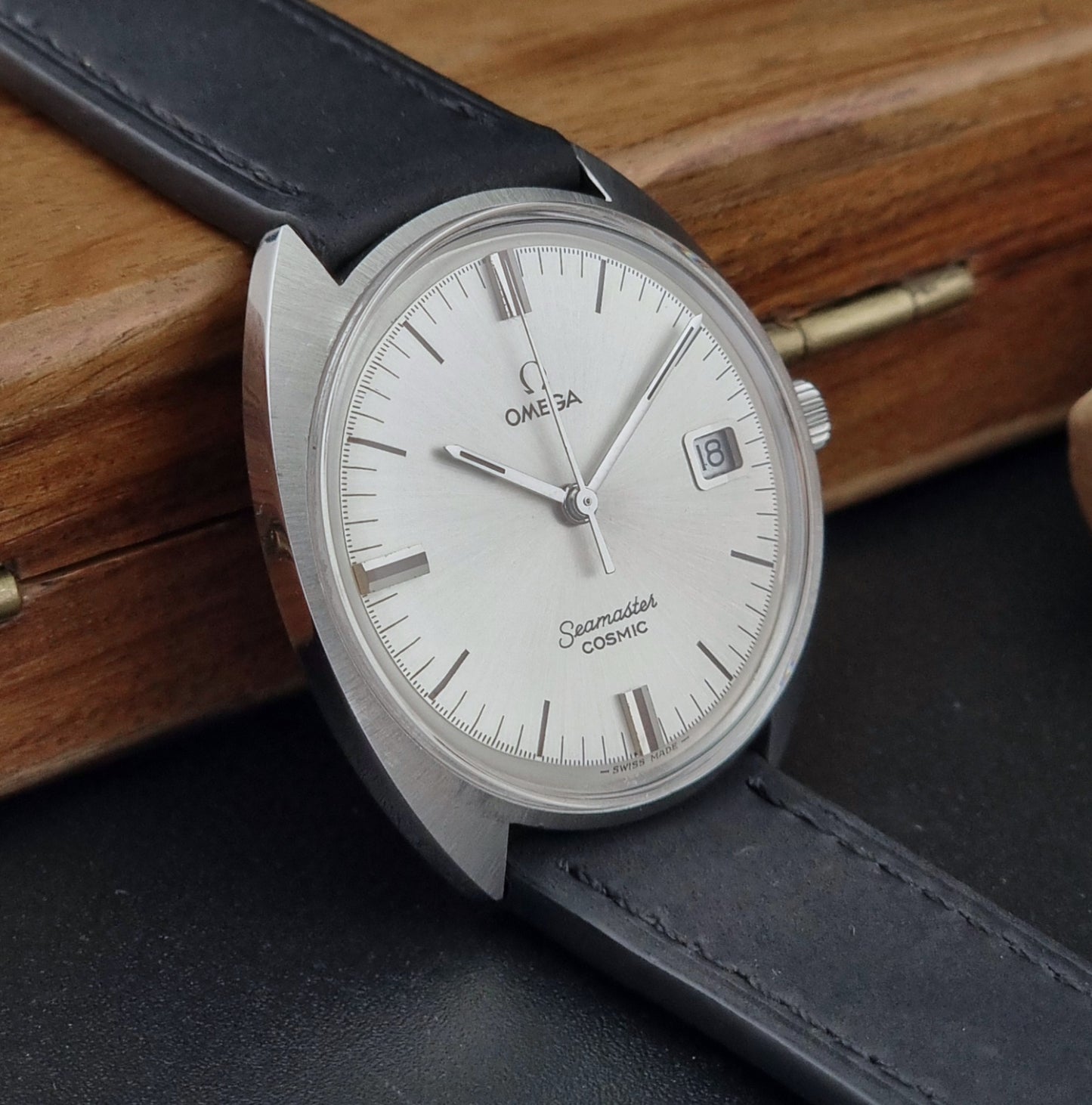 Omega Seamaster Cosmic 136.017 watch with a silver case and white dial on a wooden surface