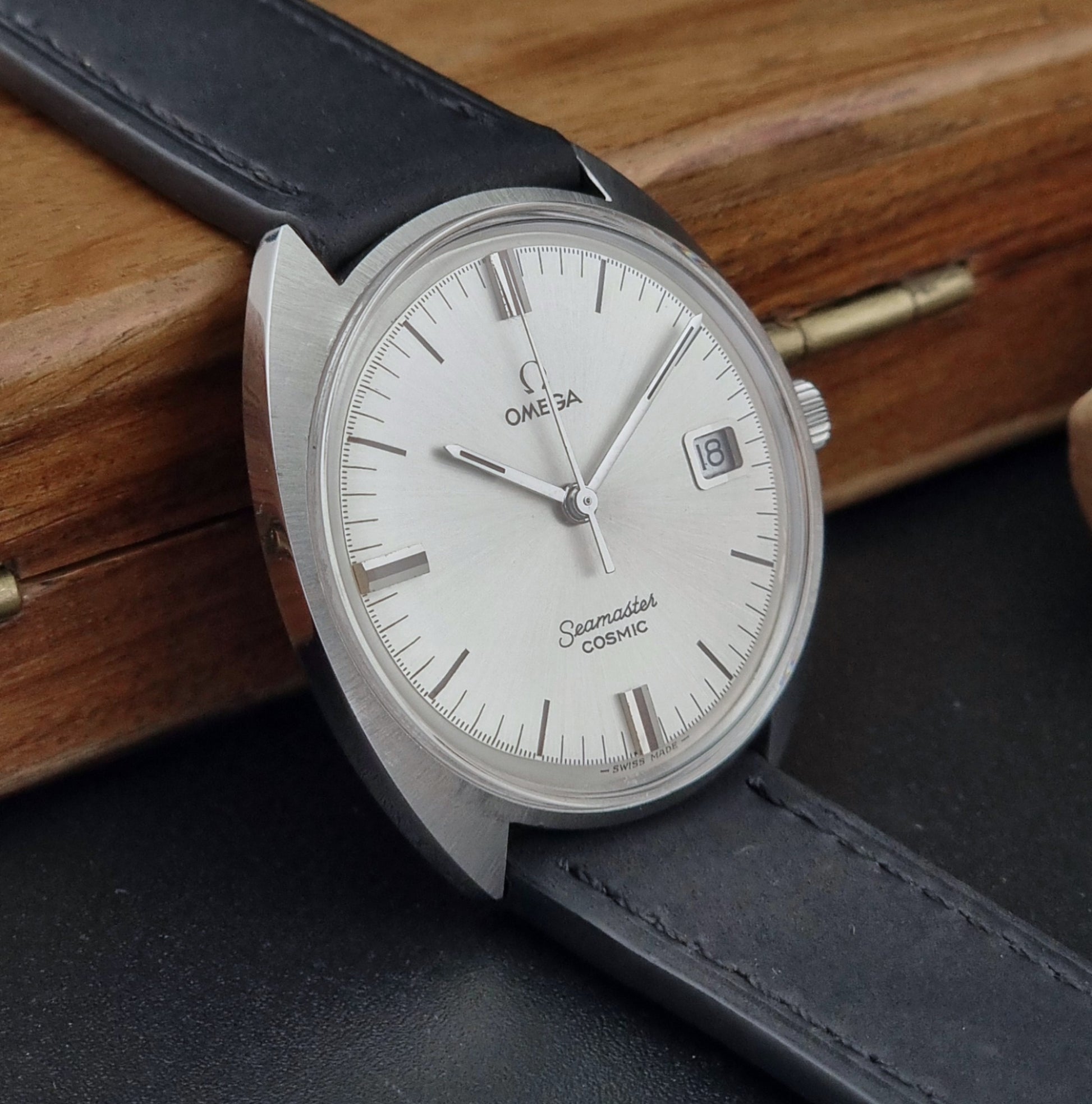 Omega Seamaster Cosmic 136.017 watch with a silver case and white dial on a wooden surface