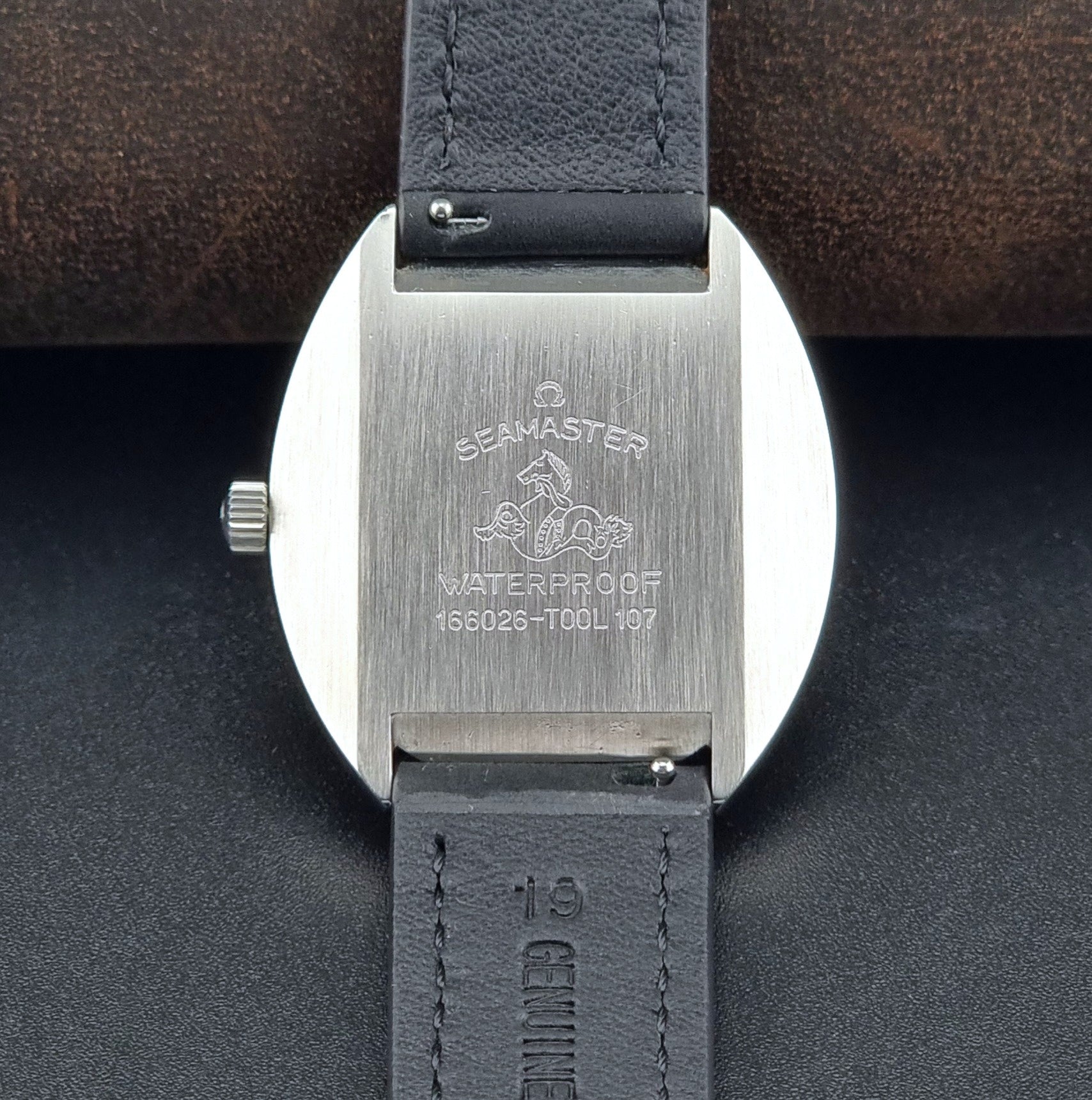 Close-up of the back of an Omega Seamaster watch with 'Seamaster' branding on a dark background