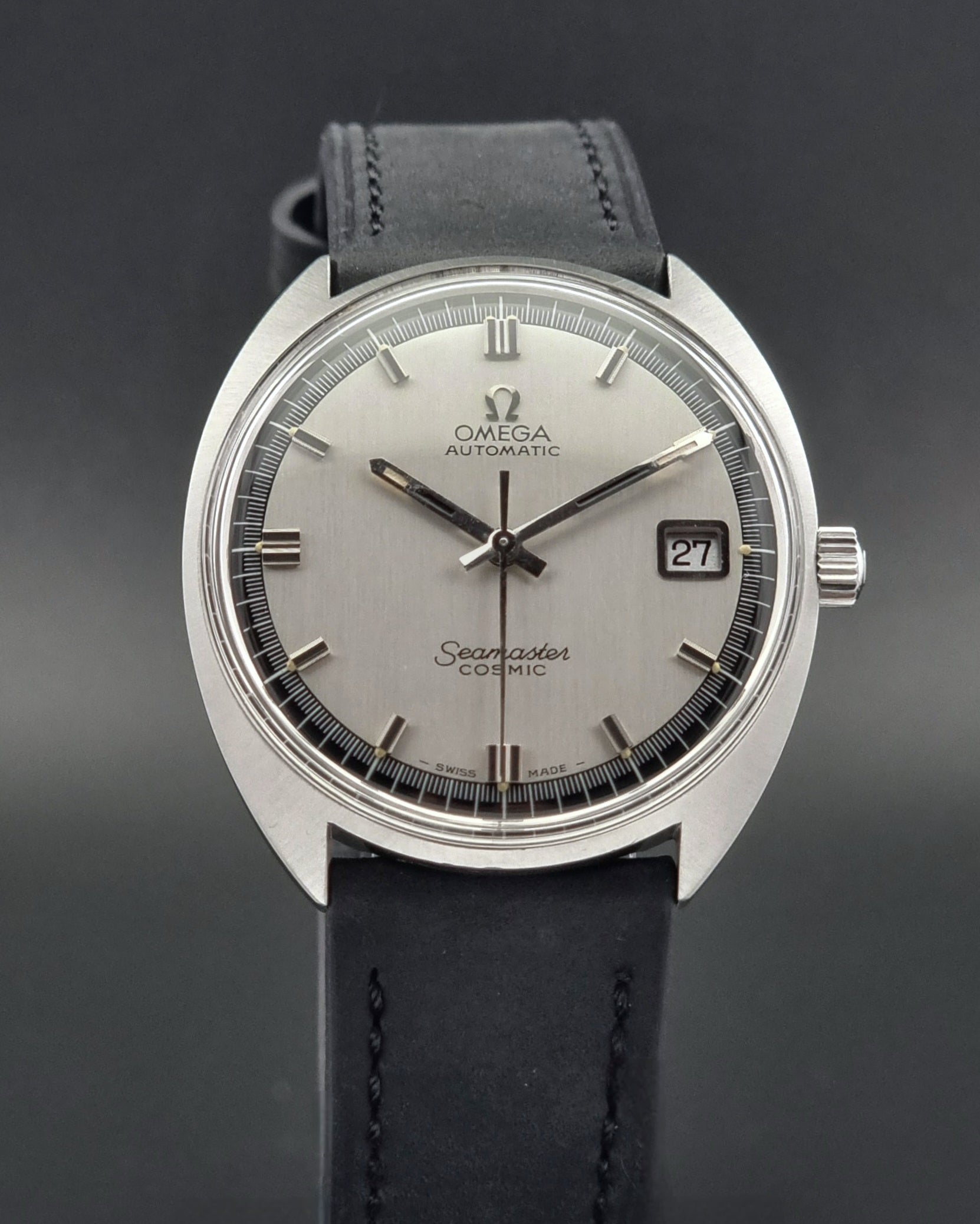 Vintage Omega Seamaster Cosmic  watch with silver dial and black leather strap on a dark background