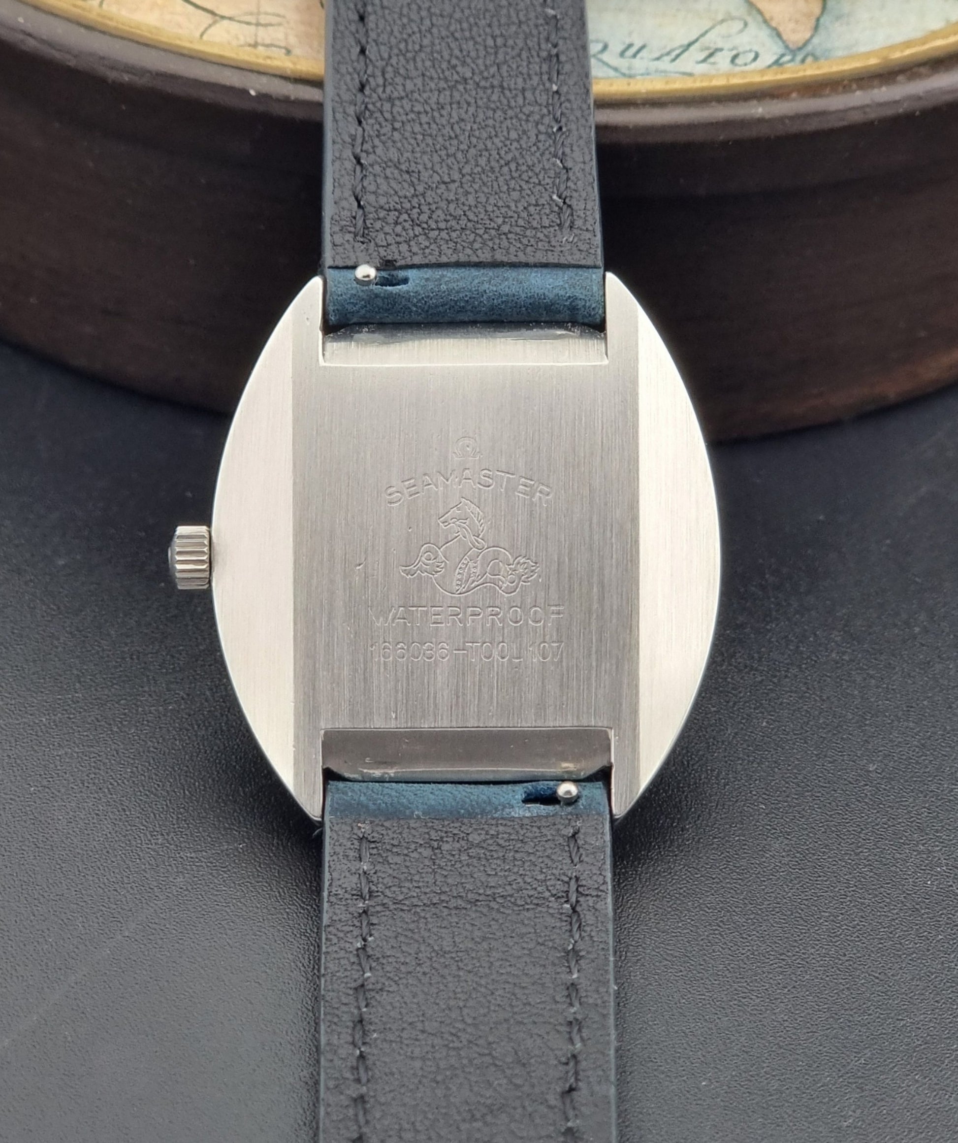Vintage Omega Wristwatch 166.036 Seamaster Cosmic with blue leather strap on a dark surface case back view