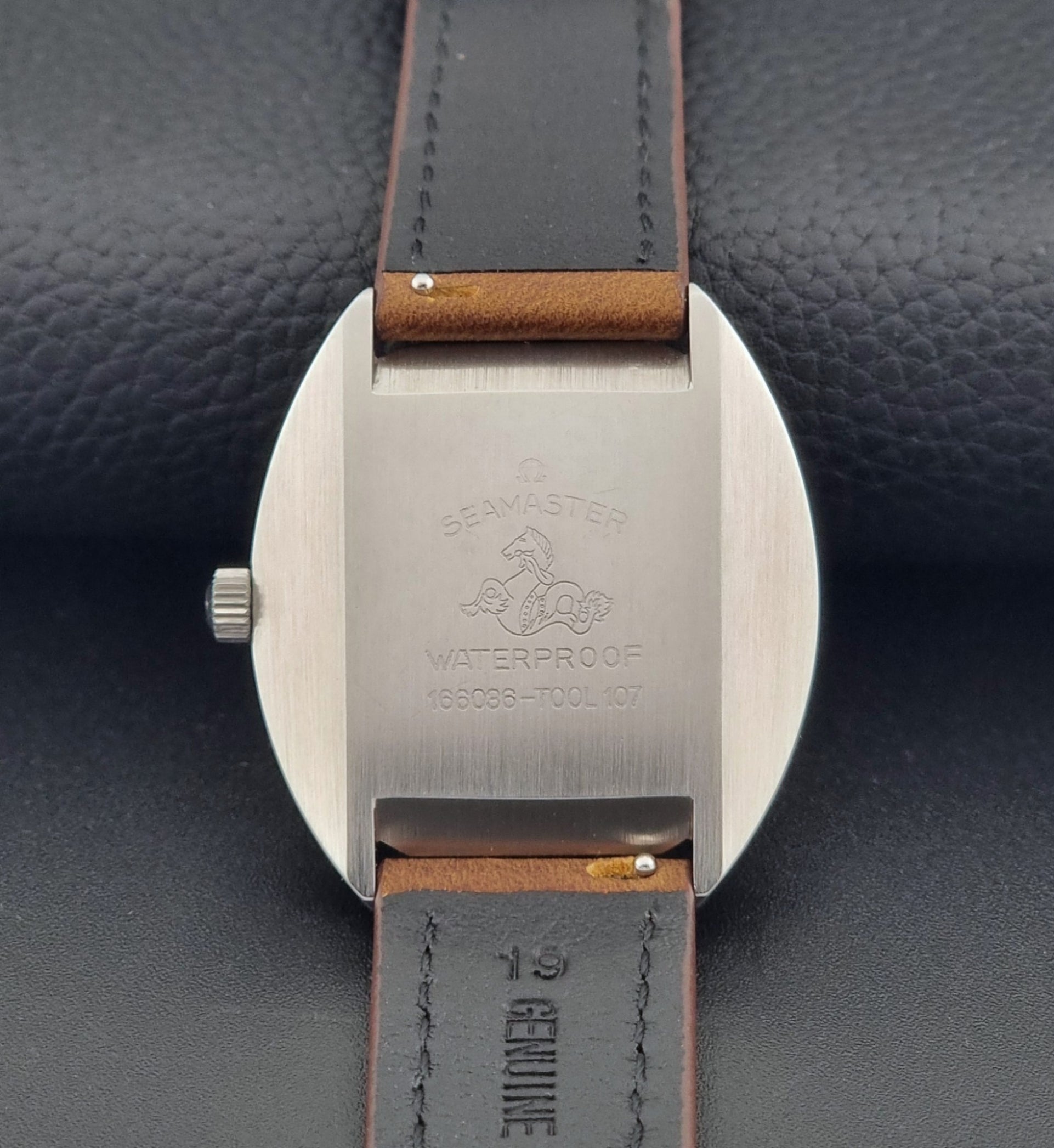 Vintage Omega Seamaster Cosmic 166.036 wristwatch with brown leather strap on a dark background case back view