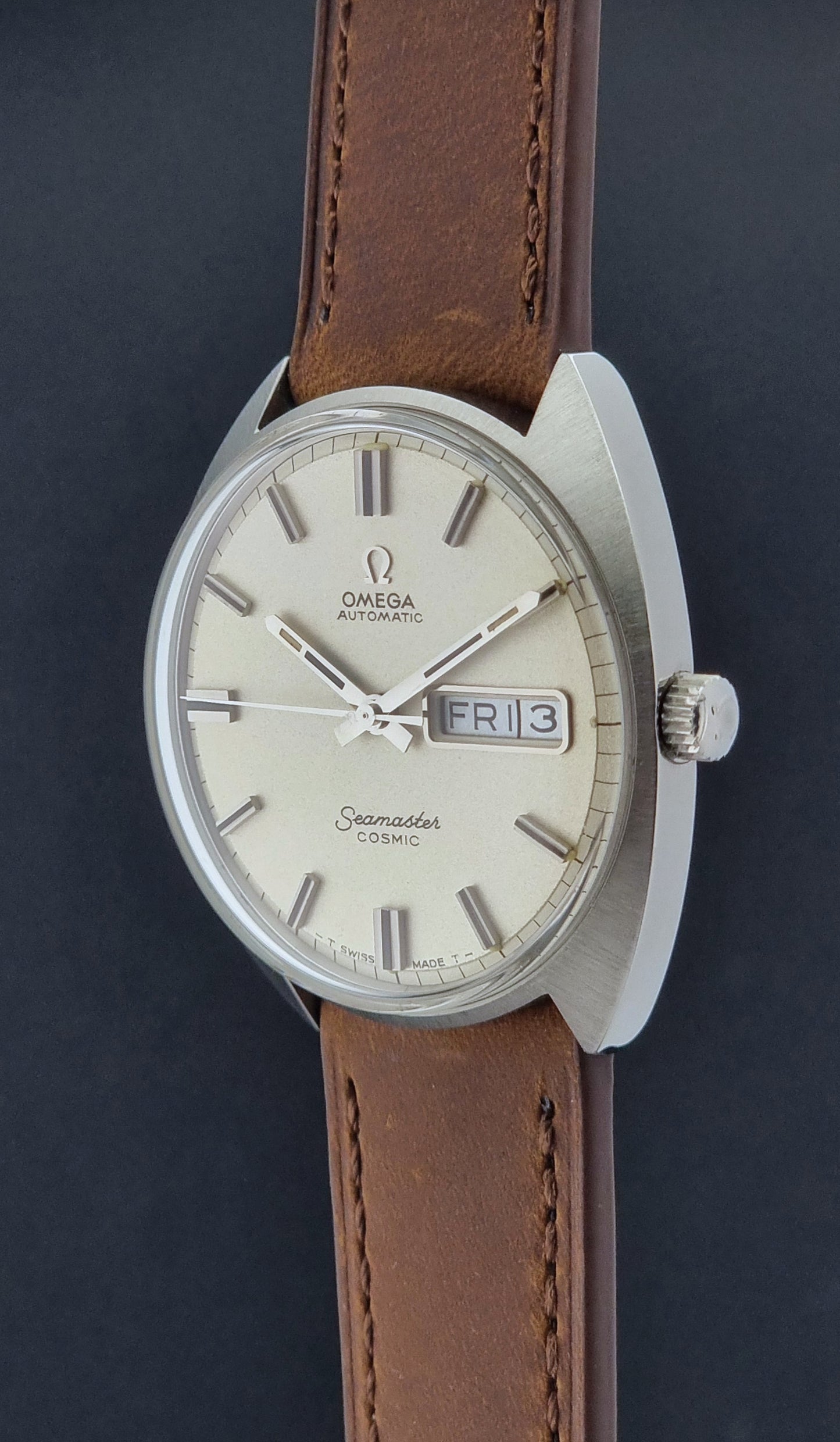 Vintage Omega Seamaster Cosmic 166.036 wristwatch with brown leather strap on a dark background crown prolife view