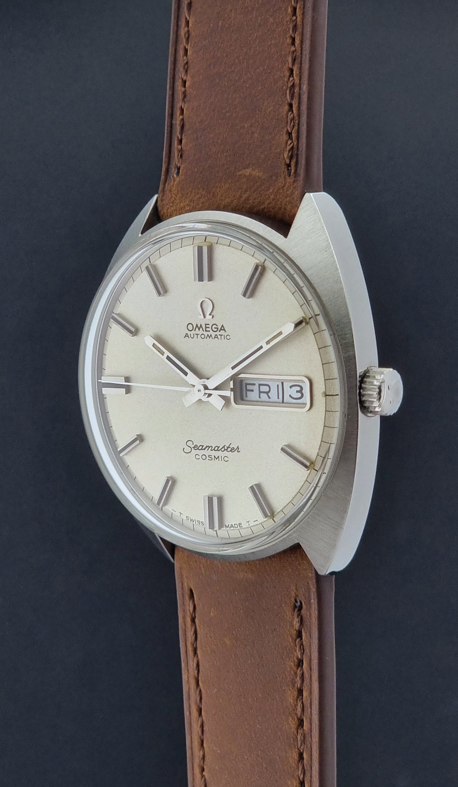 Vintage Omega Seamaster Cosmic 166.036 wristwatch with brown leather strap on a dark background crown prolife view