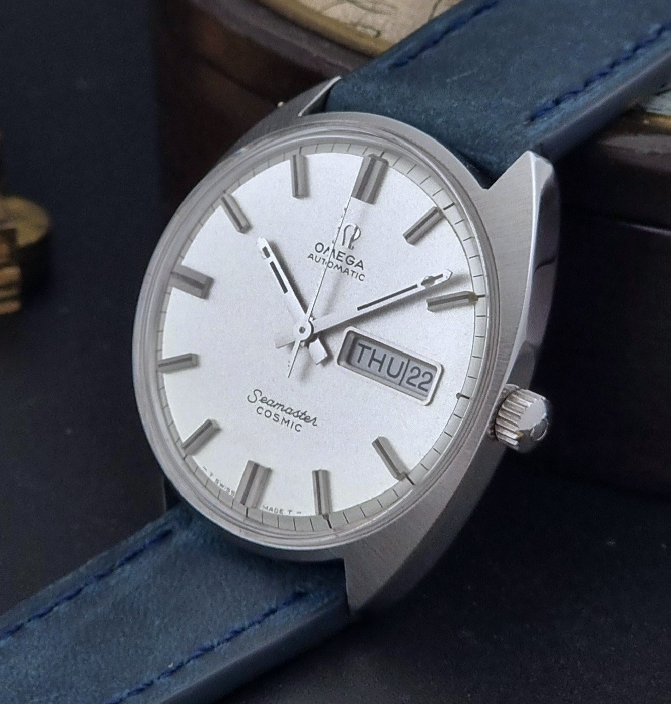 Vintage Omega Wristwatch 166.036 Seamaster Cosmic with blue leather strap on a dark surface crown view