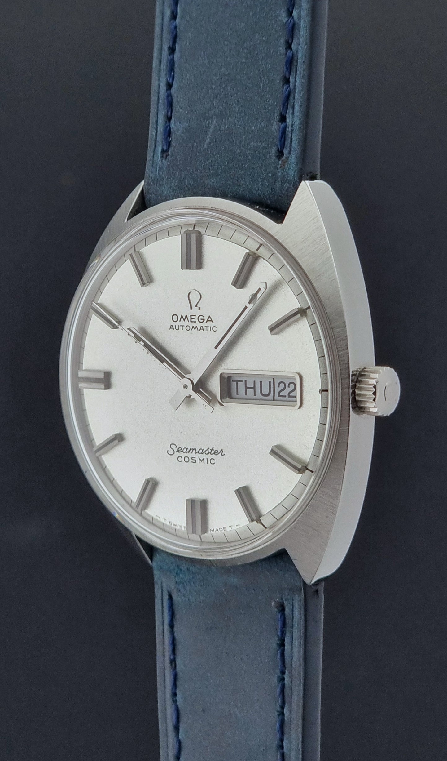 Vintage Omega Wristwatch 166.036 Seamaster Cosmic with blue leather strap on a dark surface crown profile view